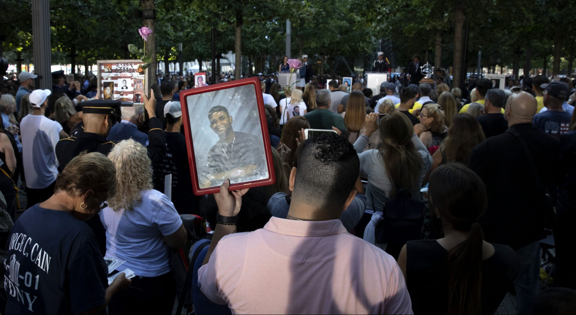 A man holds a photo of a victim during a ceremony marking the 18th anniversary of the attacks of Sept. 11, 2001, at the National September 11 Memorial, Wednesday, Sept. 11, 2019, in New York.