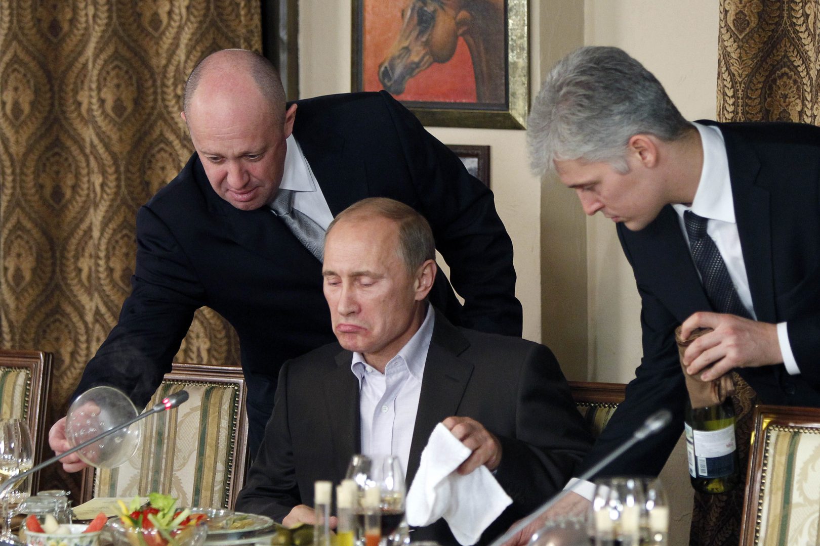 FILE - In this Friday, Nov. 11, 2011, file photo, businessman Yevgeny Prigozhin, left, serves food to Russian Prime Minister Vladimir Putin, center, during dinner at Prigozhin's restaurant outside Moscow, Russia. The U.S. sought to punish Russia on Monday, Sept. 30, 2019, for interfering with the November 2018 election by placing the yacht and private planes of a Russian financier, Yevgeny Prigozhin, on an international sanctions list along with employees of the Internet Research Agency that he has funded to spread false information on social media.