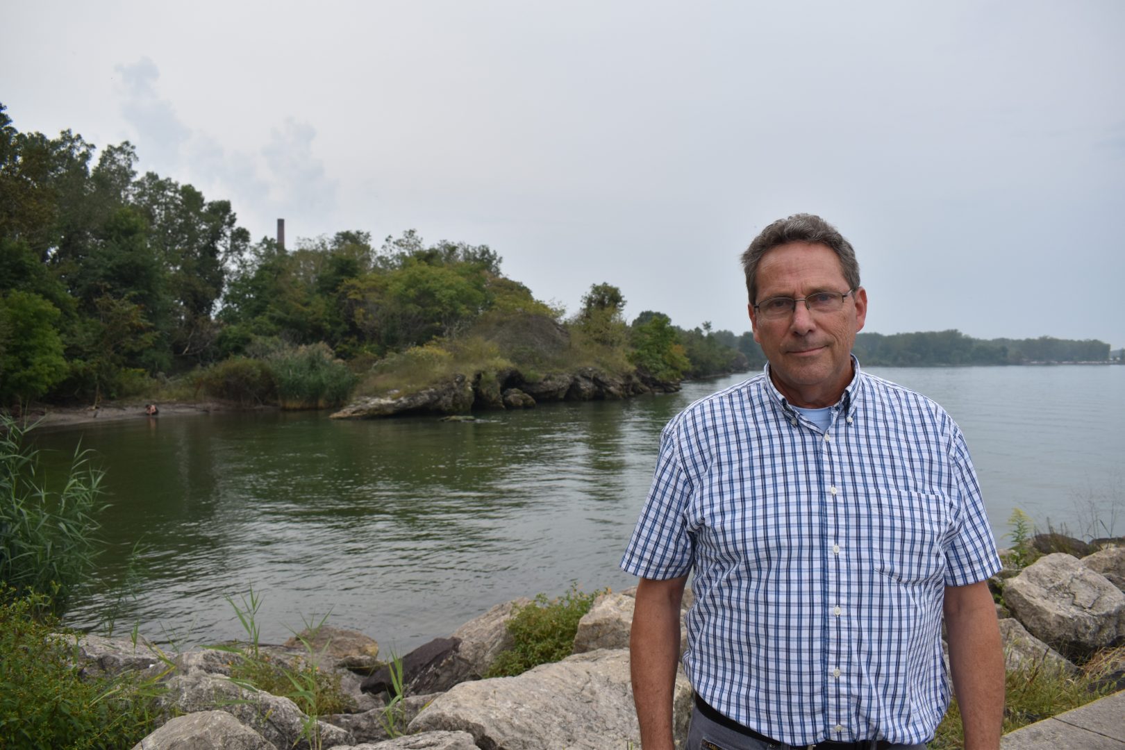 Mike Campbell, a college biology professor, is seen on Sept. 11, 2019, in a boat launch area with a smokestack of Erie Coke visible in the background.