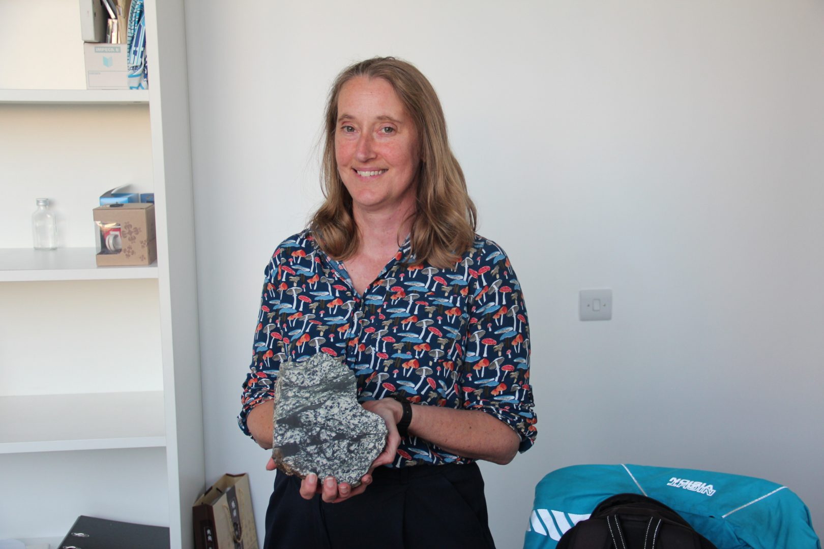 Zoe Shipton, professor of Geology, inside her office at the University of Strathclyde in Glasgow, holding a pseudotachylite from California. 