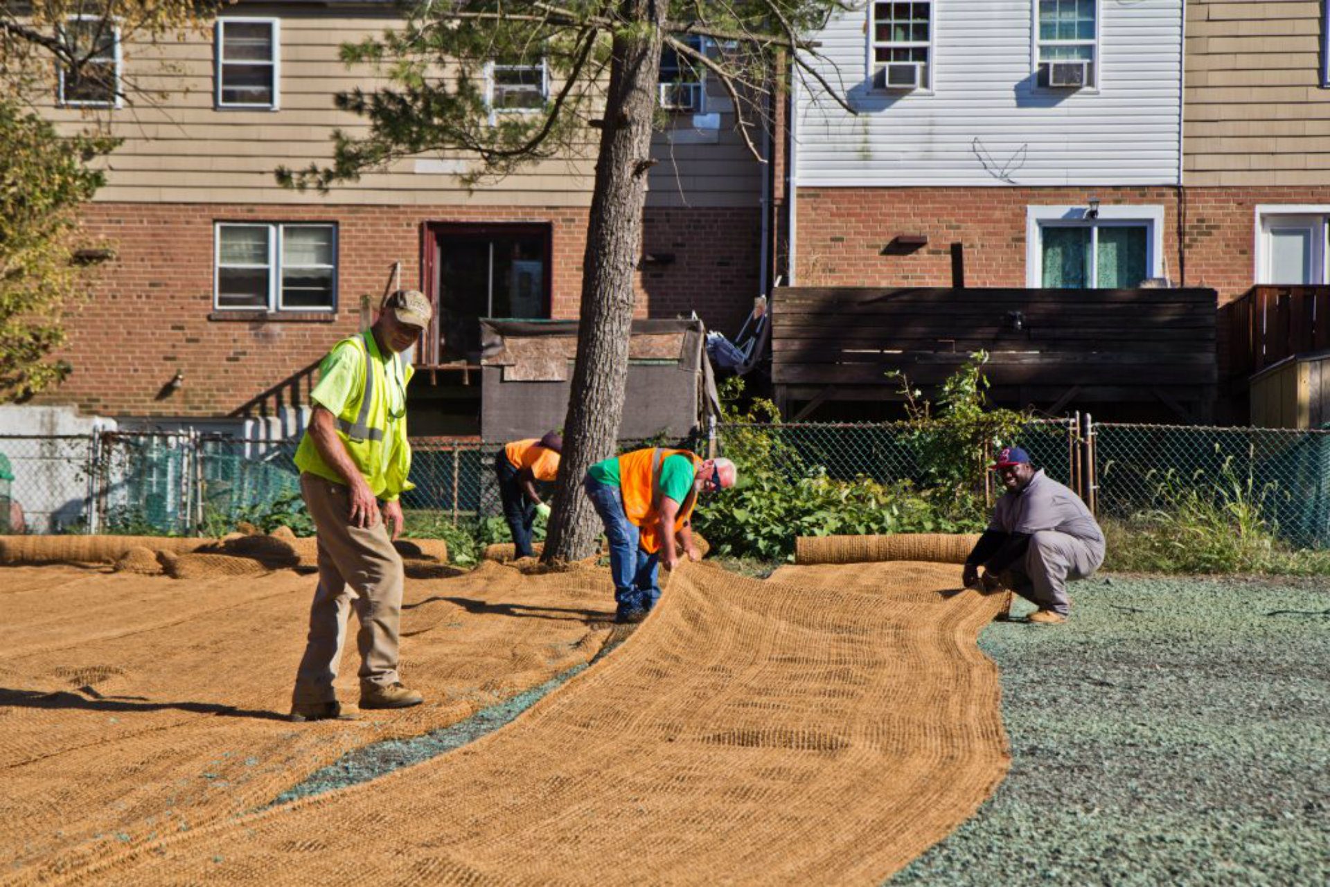 Workers lay coir matting, which is made of coconut fiber that will break down in 2-3 years, but protect hydro seed from water erosion. (Kimberly Paynter/WHYY)