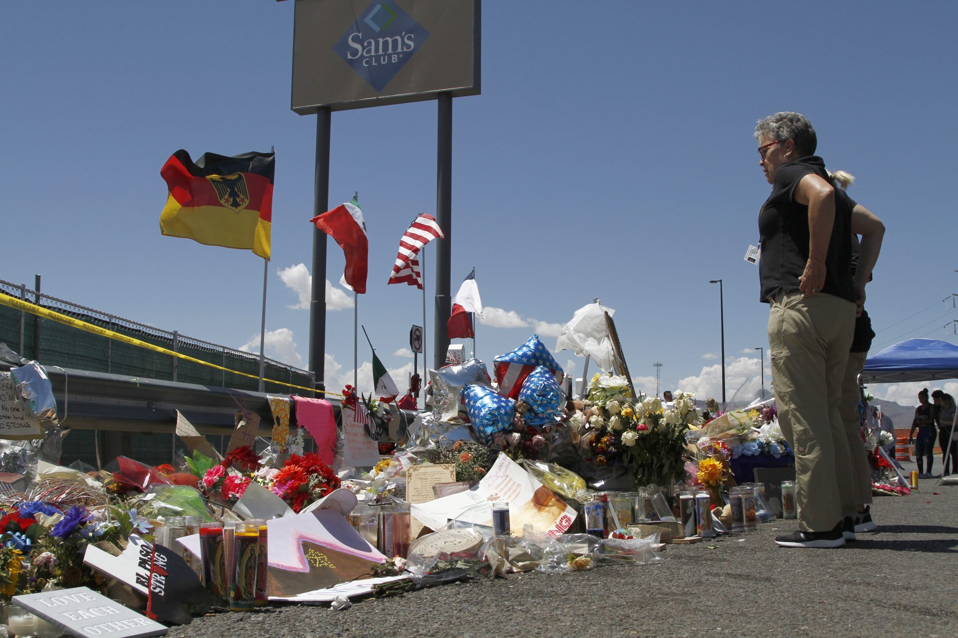 In this Aug. 12, 2019 photo, mourners visit the makeshift memorial near the Walmart in El Paso, Texas, where 22 people were killed in a mass shooting.