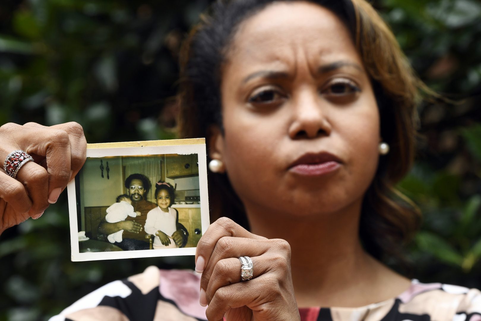 In this Sept. 6, 2019, photo, Donna Cryer holds up family photos that include her father Roland Henry, as she poses for a photo in Washington. When her father died, she tried to donate his organs, yet the local organ collection agency said no, without talking to the family or providing a reason. 