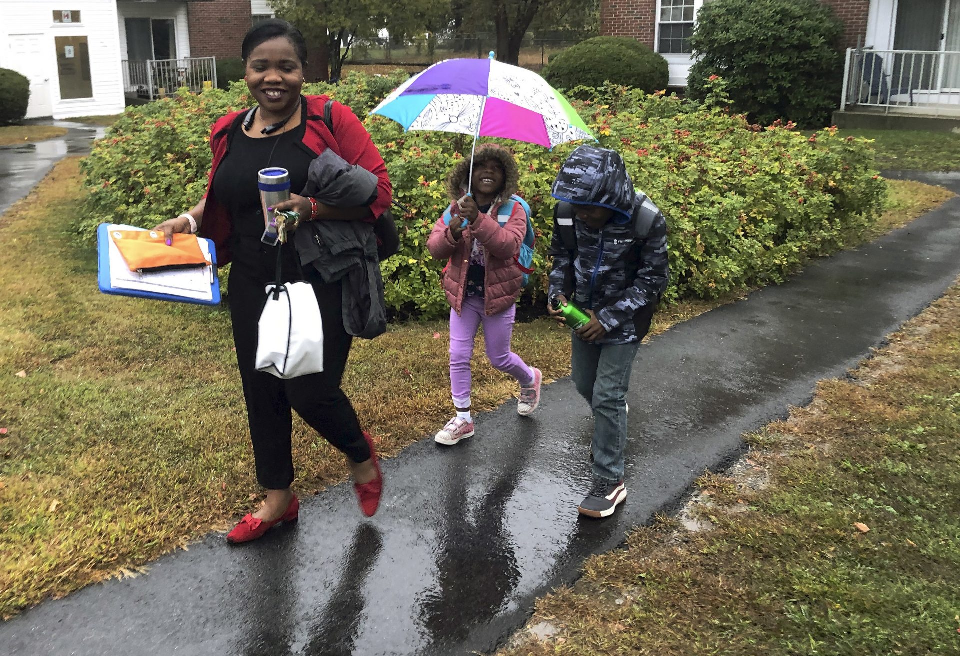 Betty Kabbashi, a medical interpreter, takes her children, Roda, 5, center, and Richie, 7, to school in the rain on Tuesday, Oct. 1, 2019, in South Portland, Maine. Kabbashi, who was a dentist in South Sudan, disagrees with President Trump's plan to further cut refugee quotas.