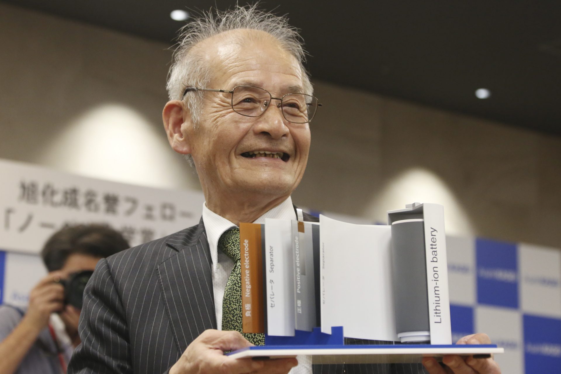 Winner of Nobel Prize in Chemistry Akira Yoshino poses a photo with a model of Lithium-ion battery during a press conference in Tokyo, Wednesday, Oct. 9, 2019. Yoshino is one of the three scientists who have won this year's Nobel Prize in Chemistry for their contributions to lithium-ion batteries, which have reshaped energy storage and transformed cars, mobile phones and many other devices in an increasingly portable and electronic world.