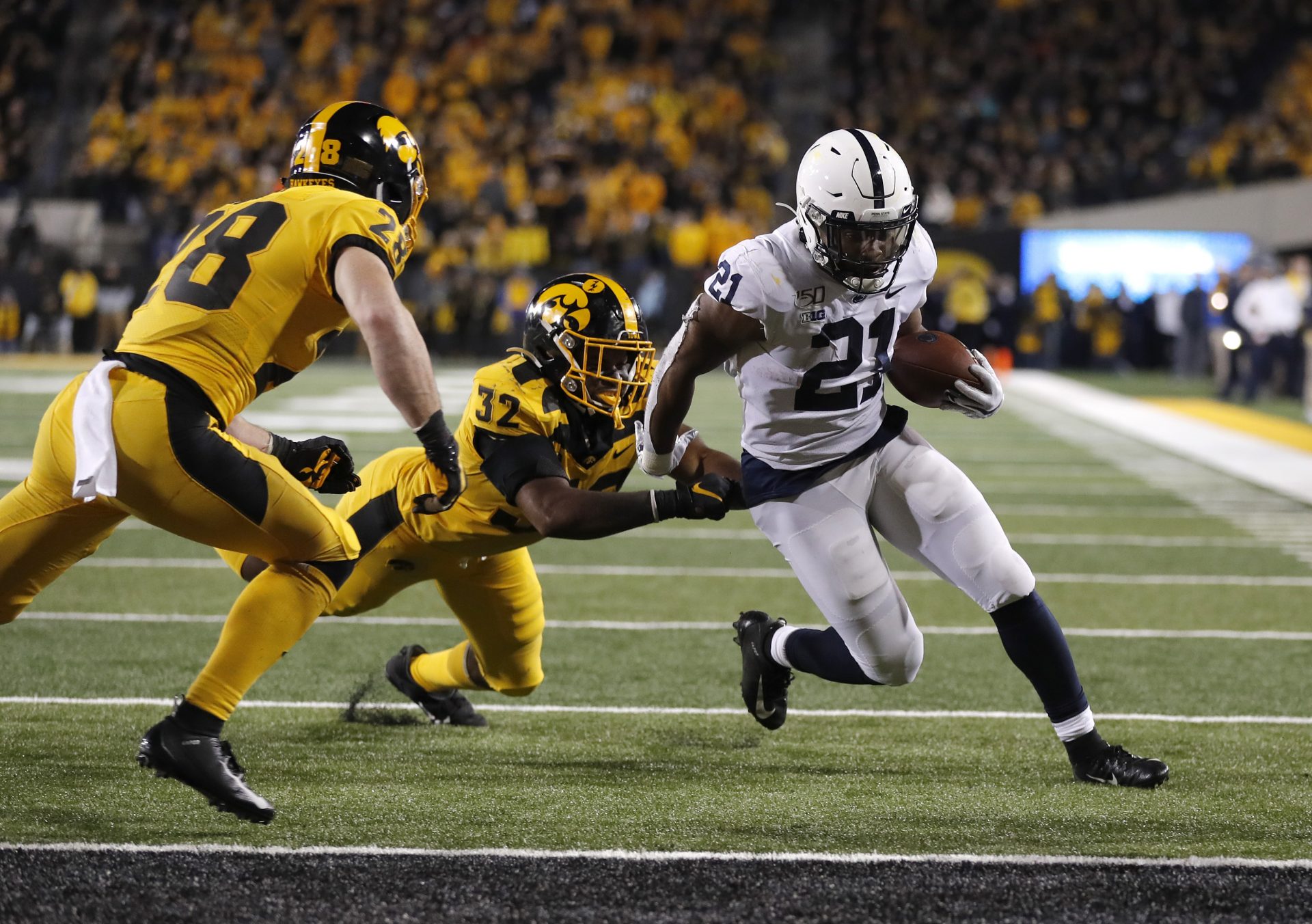 Iowa linebacker Djimon Colbert, left, loses his grasp of Penn State running back Noah Cain, right, as Cain runs in a touchdown during the second half of an NCAA college football game, Saturday, Oct. 12, 2019, in Iowa City, Iowa.