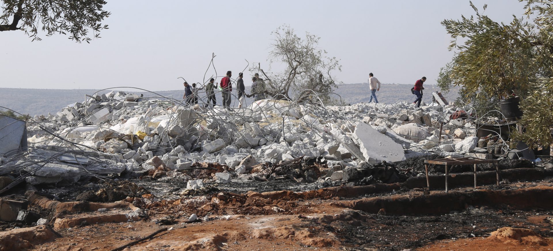 People look at a destroyed houses near the village of Barisha, in Idlib province, Syria, Sunday, Oct. 27, 2019, after an operation by the U.S. military which targeted Abu Bakr al-Baghdadi, the shadowy leader of the Islamic State group. President Donald Trump says Abu Bakr al-Baghdadi is dead after a U.S. military operation in Syria targeted the Islamic State group leader.