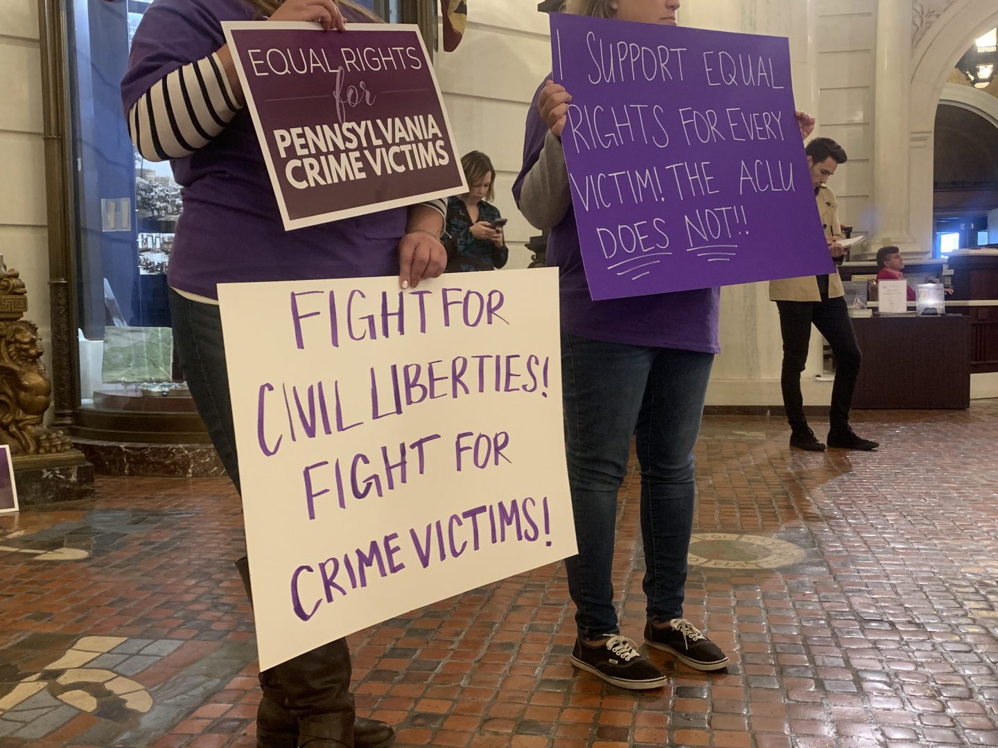 Supporters of Marsy's Law held signs in protest during the ACLU's press conference announcing its lawsuit.