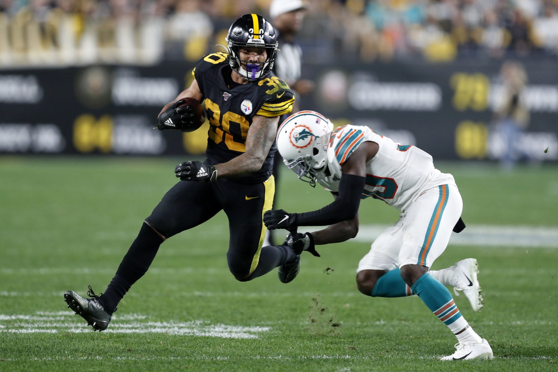 Pittsburgh Steelers running back James Conner (30) runs around Miami Dolphins defensive back Chris Lammons (30) during the second half of an NFL football game in Pittsburgh, Monday, Oct. 28, 2019.