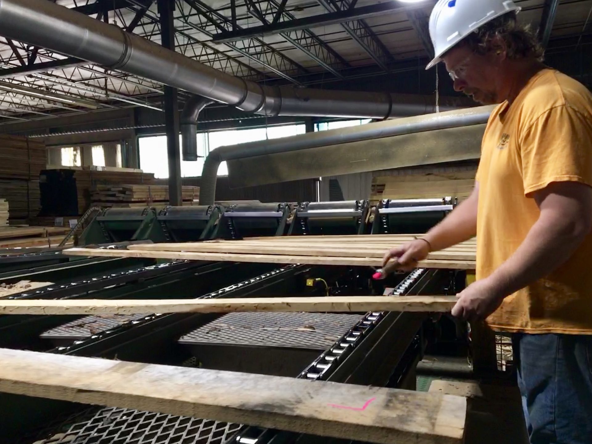 An employee at Collins Hardwood in Kane, Pennsylvania, sorts and marks the wood. The ongoing trade war with China is taking a toll on the hardwood industry in Pennsylvania and nationally.