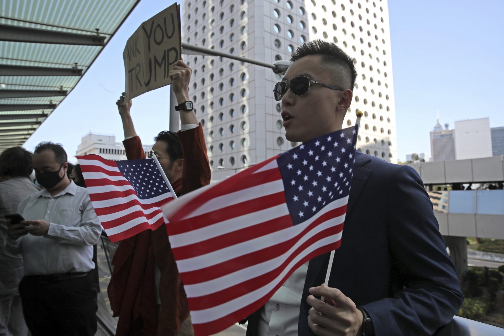 Protesters hold American flags and placard during a demonstration in Central, the financial district of Hong Kong, Thursday, Nov. 28, 2019. China reacted furiously to President Donald Trump's signing of two bills on Hong Kong human rights and said the U.S. will bear the unspecified consequences. A foreign ministry statement Thursday repeated heated condemnations of the laws and said China will counteract. It said all the people of Hong Kong and China oppose the move.