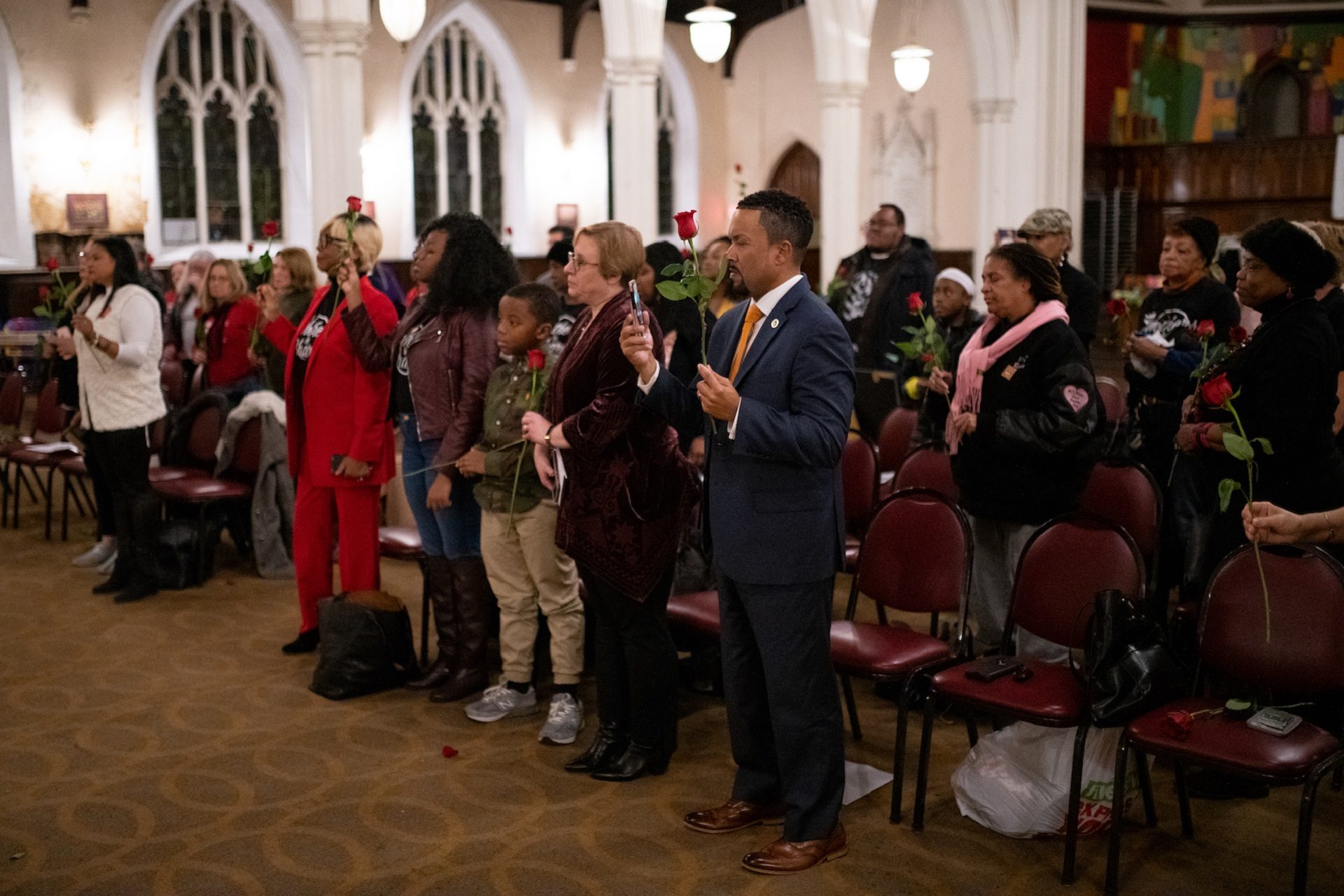 A group gathered to remember gun violence victims stands, vowing not to stop pursuing change, during a vigil at Broad Street Ministry on Wednesday, December 11, 2019.