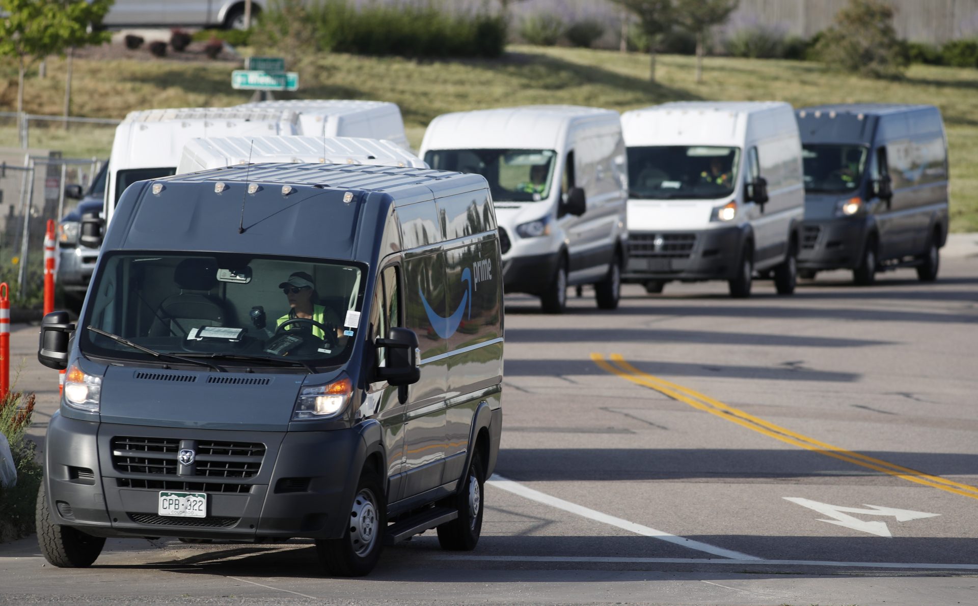 In this Tuesday, July 30, 2019, file photograph, vans queue up to leave an Amazon delivery center in suburban Englewood, Colo.