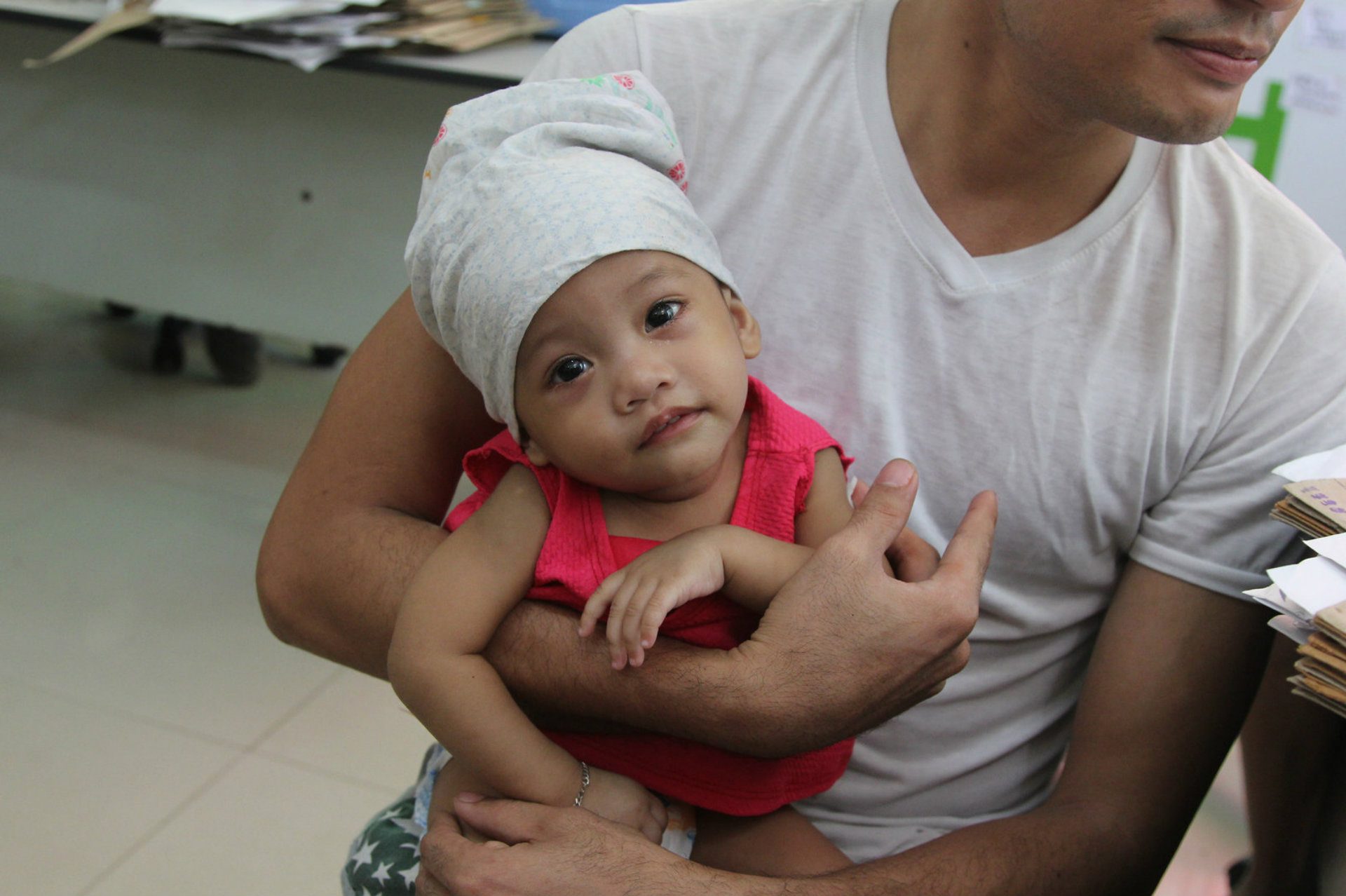 A father in the Philippines holds his child, who was immunized for measles.
