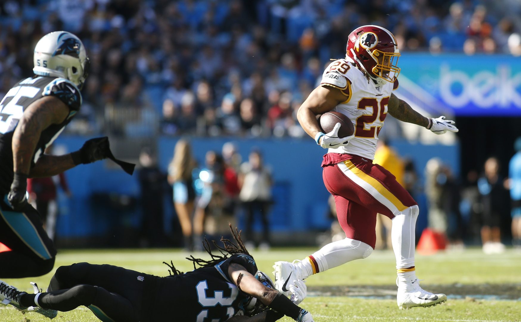 Washington Redskins running back Derrius Guice (29) runs the ball while Carolina Panthers free safety Tre Boston (33) dives to tackle during the first half of an NFL football game in Charlotte, N.C., Sunday, Dec. 1, 2019. 