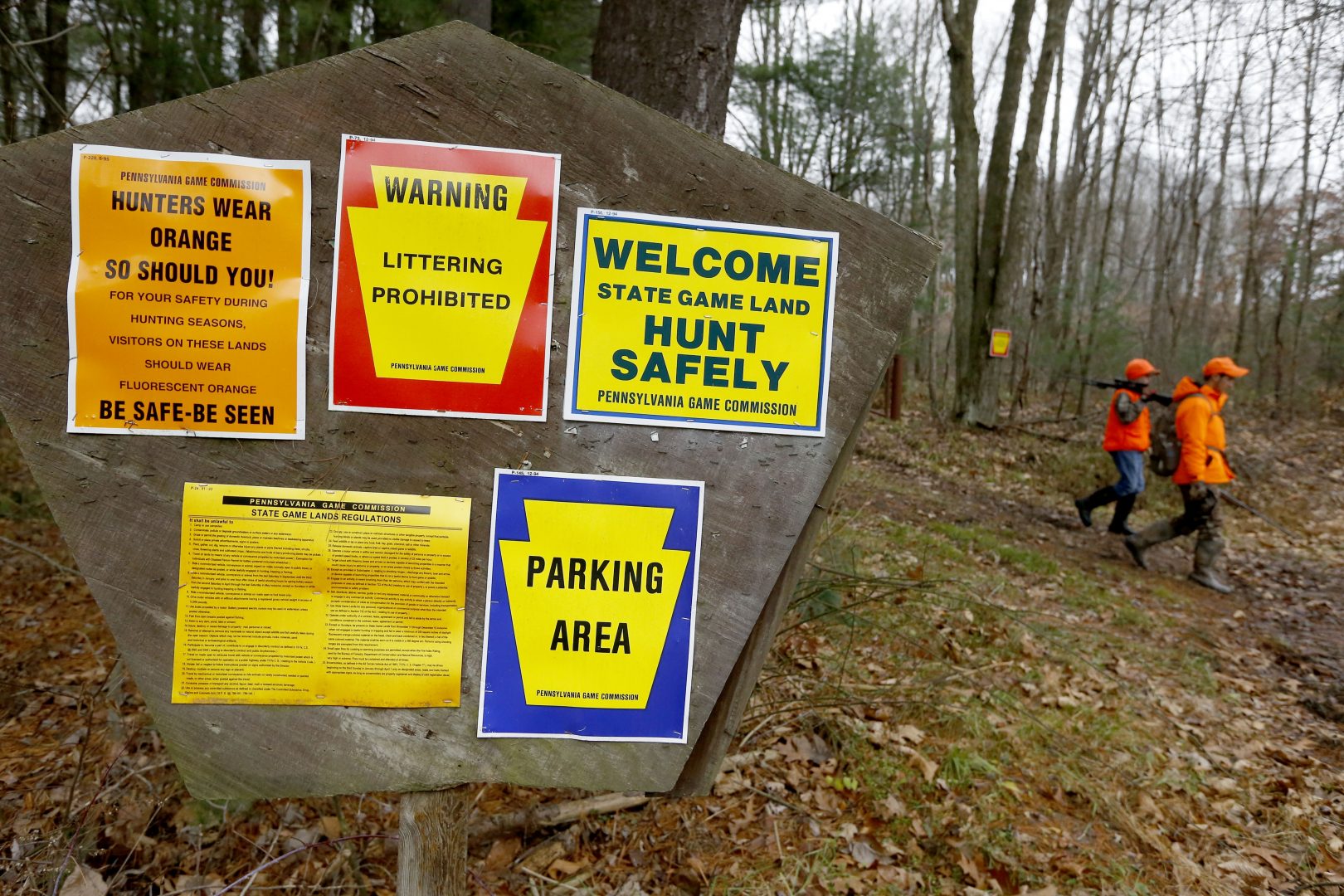 FILE PHOTO: Hunters carrying firearms walk past posted regulations on the state game lands while heading to their cars during the first day of Pennsylvania's white-tailed deer hunting season Monday, Dec. 1, 2014, in Butler, Pa. 