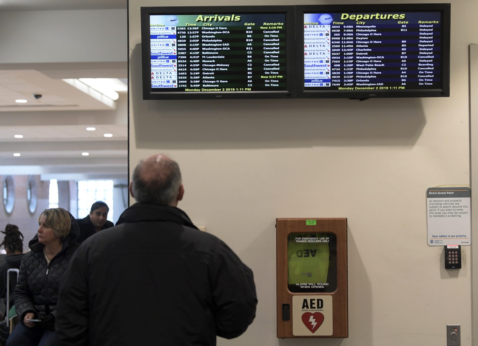 A man looks at a flight status board as flight service resumes after an overnight snowfall, at the Albany International Airport in Colonie, N.Y., Monday, Dec. 2, 2019.