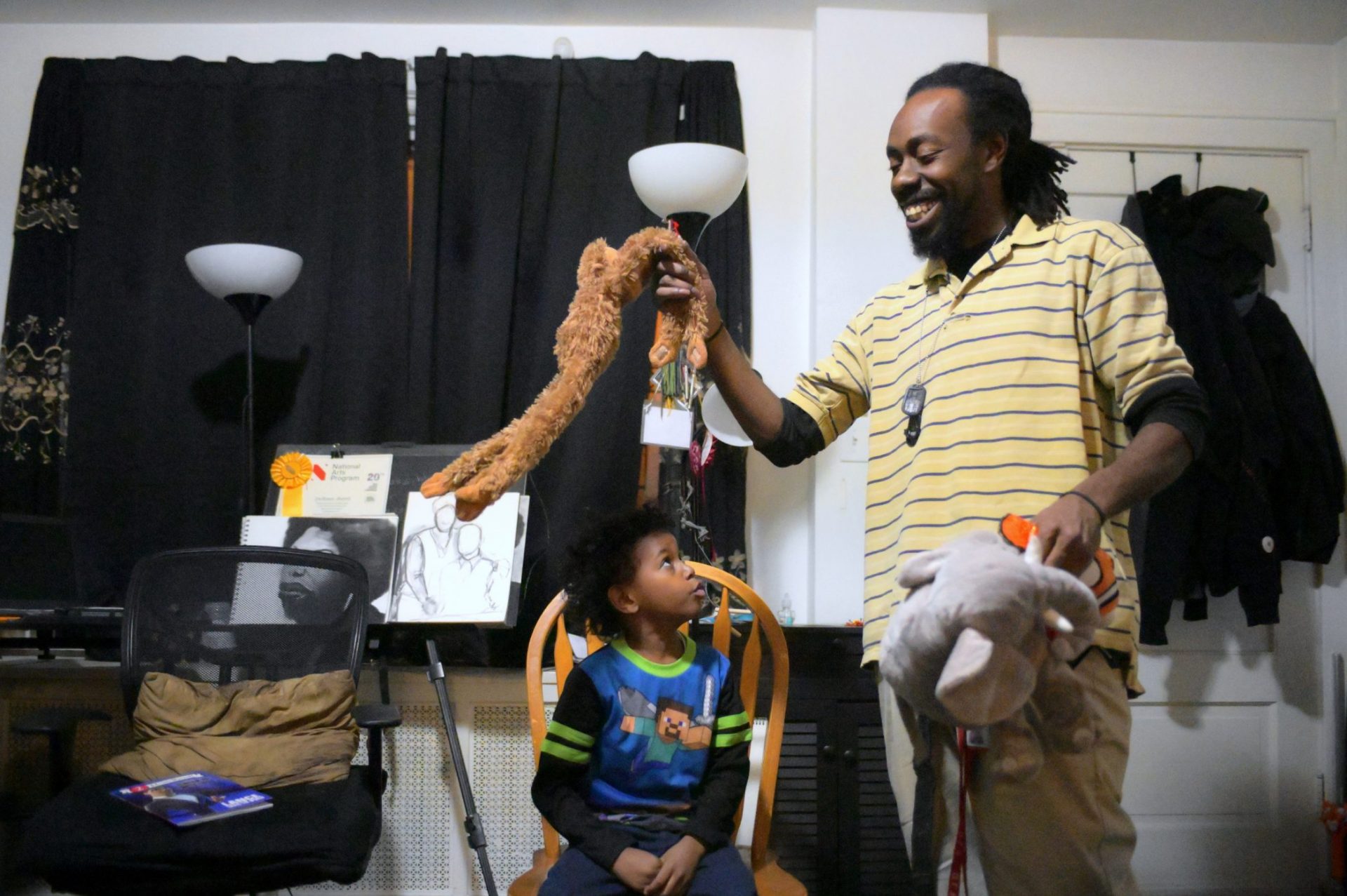 Single parent Deshaun Sherrill and his son Zay’ion Ventura-Sherrill clean up the living room of their home in West Philadelphia.