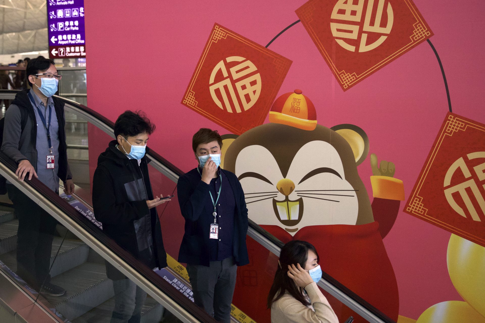 People wear face masks as they ride an escalator on Tuesday at the Hong Kong International Airport.