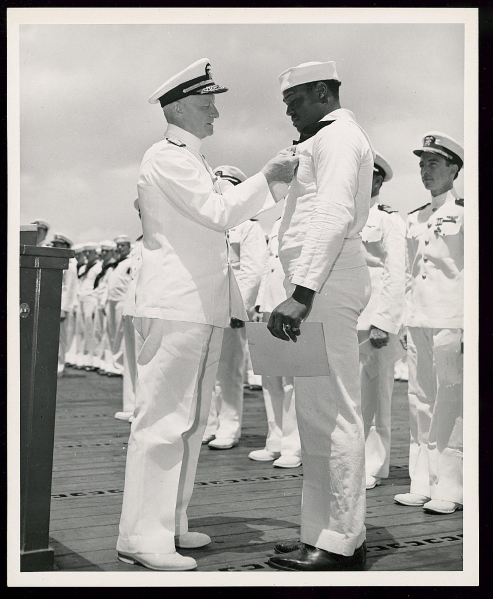 Admiral Chester W. Nimitz, Commander-in-Chief of the U.S. Pacific Fleet, pins the Navy Cross on Miller at a ceremony on board a U.S. Navy warship in Pearl Harbor on May 27, 1942. 