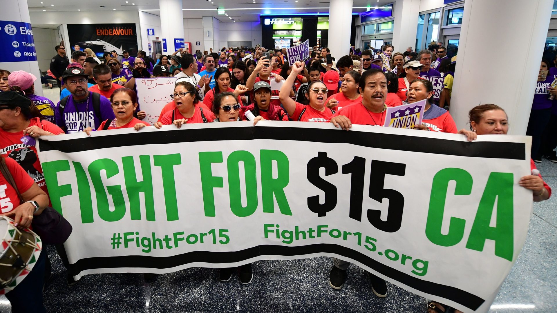 Airport employees, Uber and Lyft drivers, and other workers protest for a $15 minimum wage at Los Angeles International Airport in October. Increases in minimum wages contributed to bigger pay gains for lower-income workers.