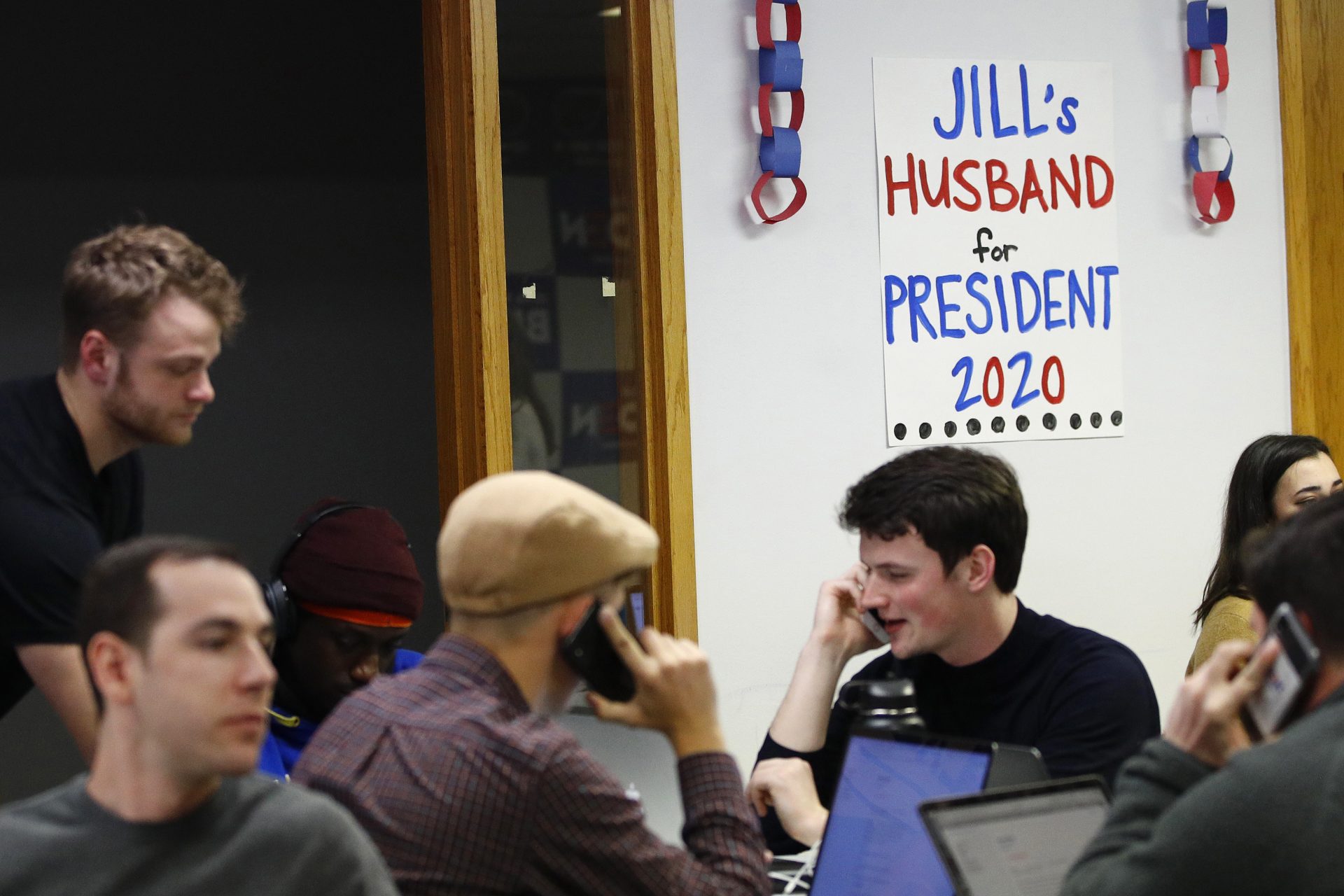 A poster for Democratic presidential candidate former Vice President Joe Biden hangs behind volunteers as they call potential caucus-goers from a campaign field office, Monday, Jan. 13, 2020, in Des Moines, Iowa.