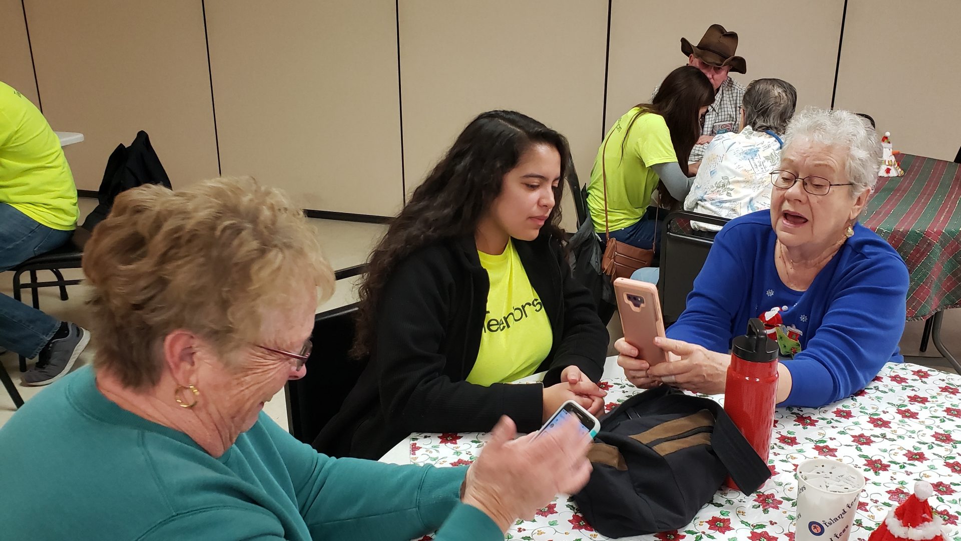 Kendra Gonzales coaches Linda Haverty on how to add a photo of a friend to her contacts list on her phone.