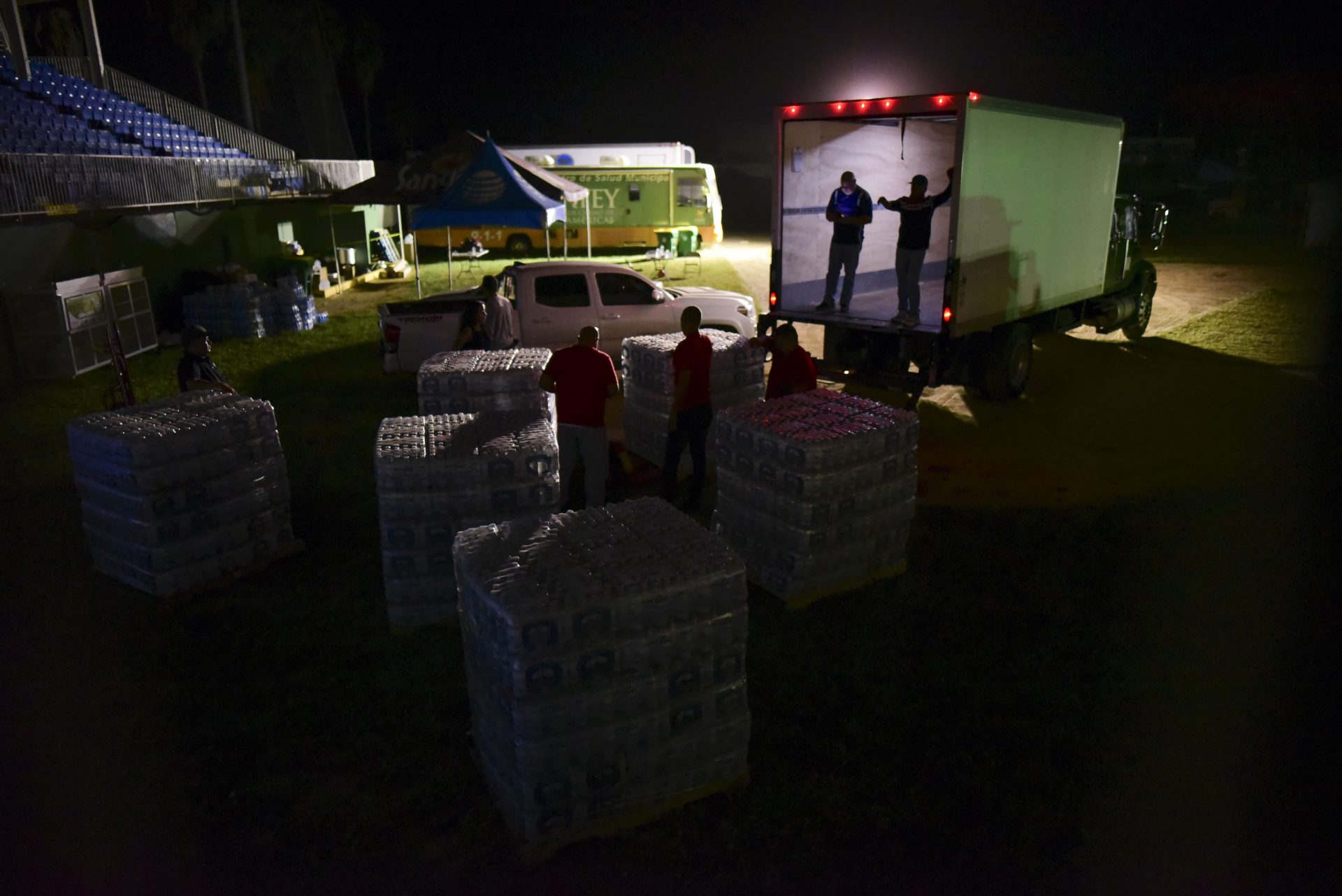Volunteers deliver boxes of water to a baseball stadium that has been opened as a shelter to residents who lost their homes in a 6.4 magnitude earthquake, in Guayanilla, Puerto Rico, late Thursday, Jan. 9, 2020. Hundreds of thousands of Puerto Ricans are still without power and water, and thousands are staying in shelters and sleeping on sidewalks since Tuesday's earthquake.