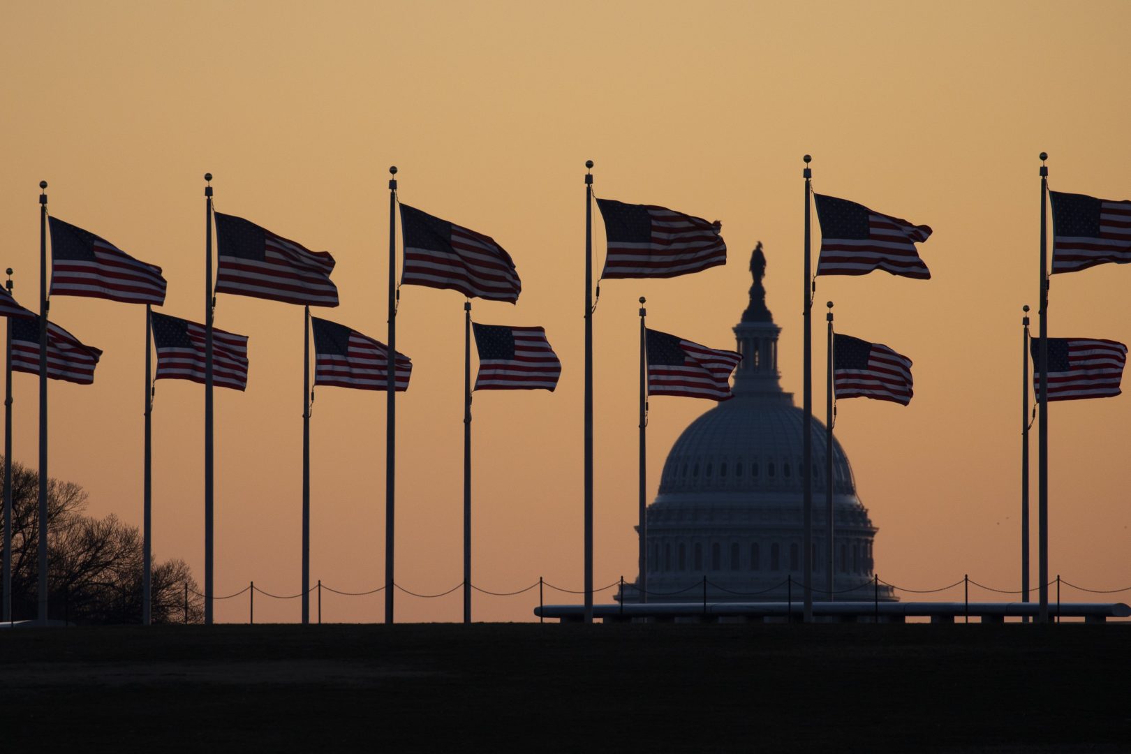 American flags blow in wind around the Washington Monument with the U.S. Capitol in the background at sunrise on Monday, Jan. 20, 2020, in Washington. The impeachment trial of President Donald Trump will resume in the U.S. Senate on Jan. 21. 