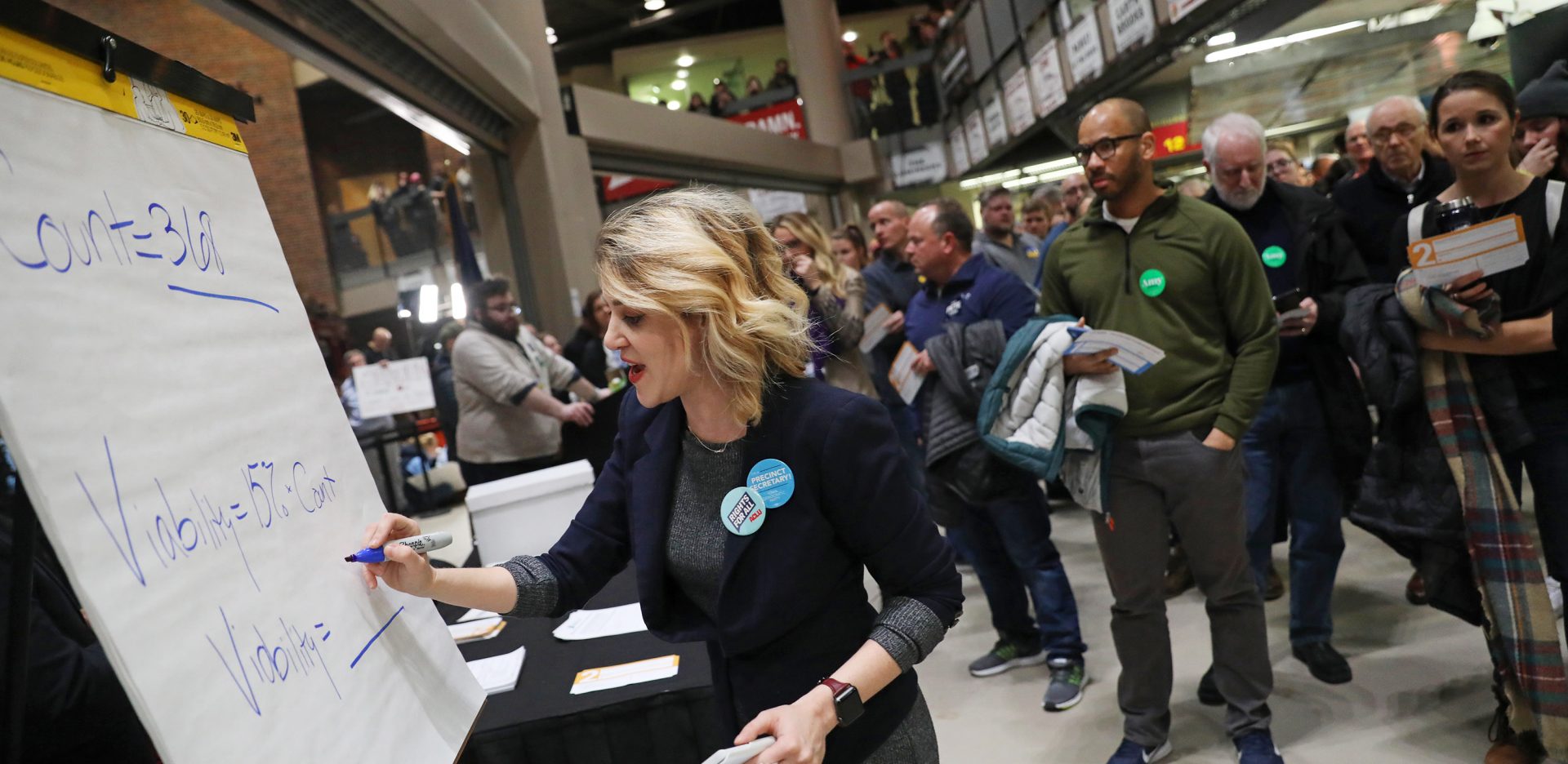 Precinct secretary Ari Fleisig writes in the number of people needed for a candidate to be viable at a caucus precinct site in Des Moines, Iowa on Monday night.