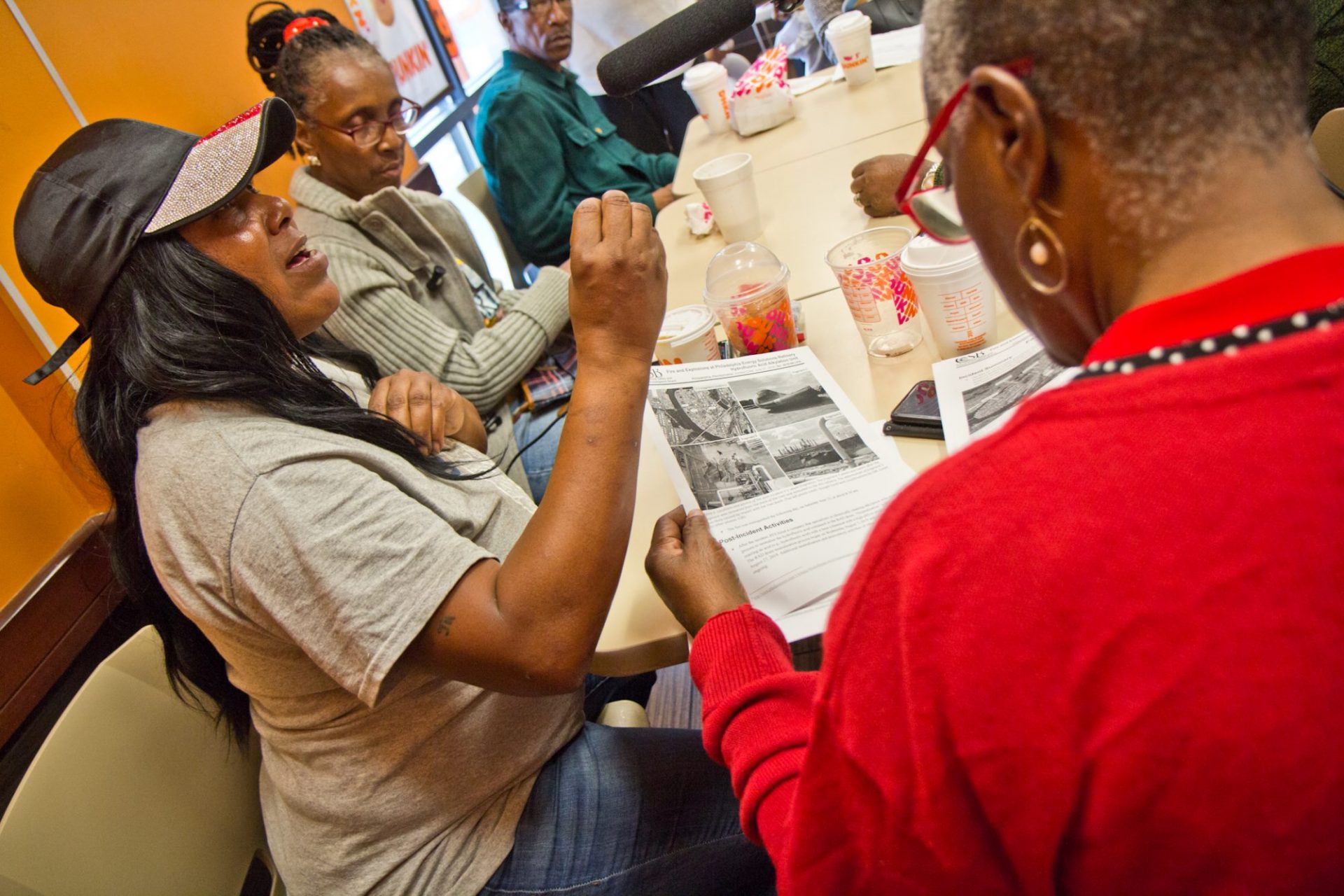 Sonya Sanders, (left), who lives near the Philadelphia Energy Solutions complex in South Philadelphia, reads the Chemical Safety Board’s report on the refinery fire. (Kimberly Paynter/WHYY)