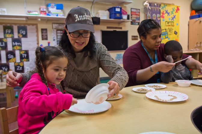 Kids in SPIN’s autism support preschool classroom work on their motor skills by creating a marshmallow fluff and Cheerio heart craft project.