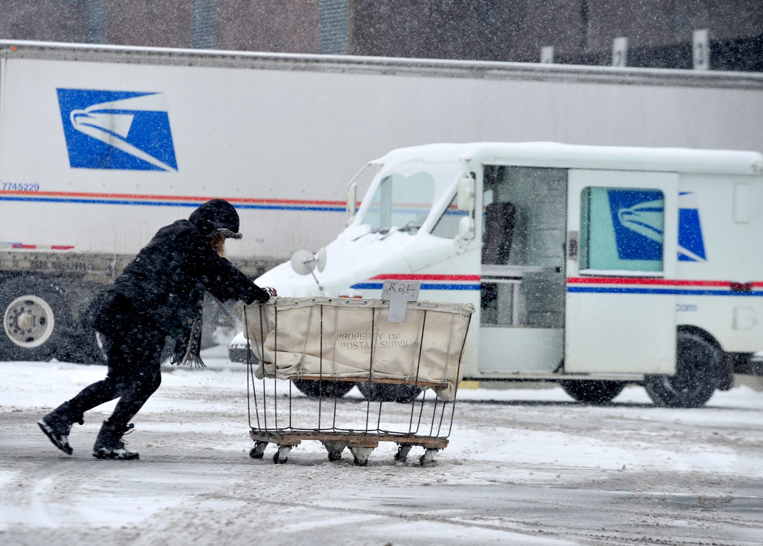 FILE PHOTO: USPS carrier Stephanie Starr pushes a mail cart from her carrier vehicle to the loading dock area of the Columbus, Ind. Post Office, Tuesday, Feb. 9, 2010. Starr said that although she is used to delivering in inclement weather, her rural route takes about two hours longer to complete when there is heavy snow.