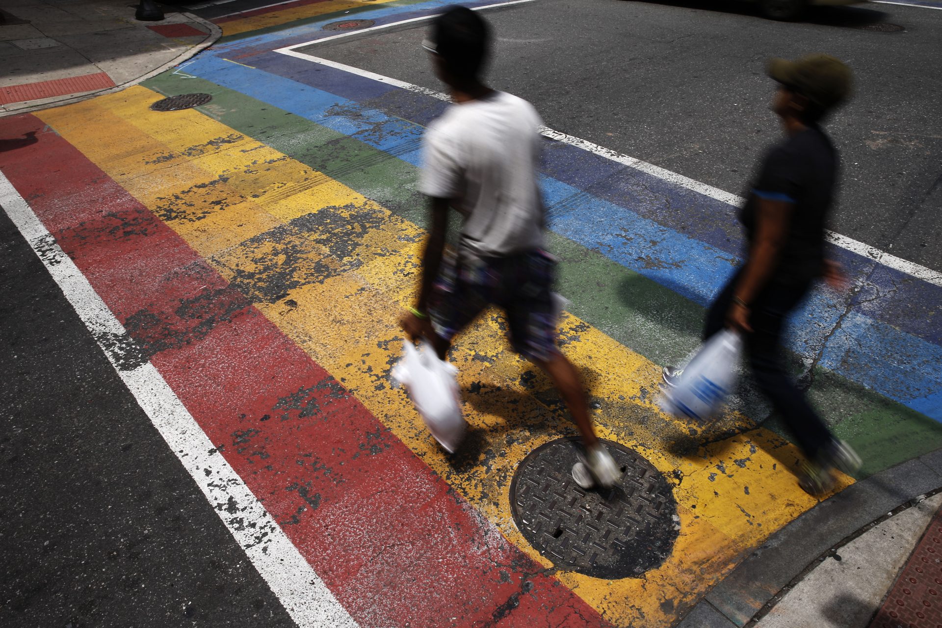 People walk across a rainbow crosswalk painted in support of the LGBT community at the intersection of 13th and Locust streets in Philadelphia, Friday, June 17, 2016.