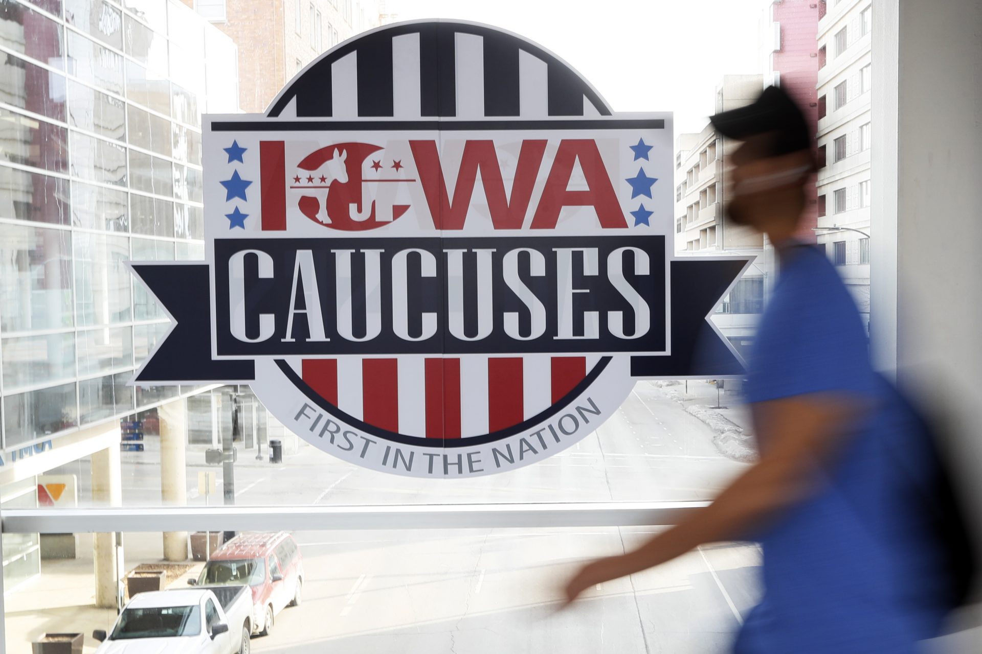 A pedestrian walks past a sign for the Iowa Caucuses on a downtown skywalk, Tuesday, Feb. 4, 2020, in Des Moines, Iowa.