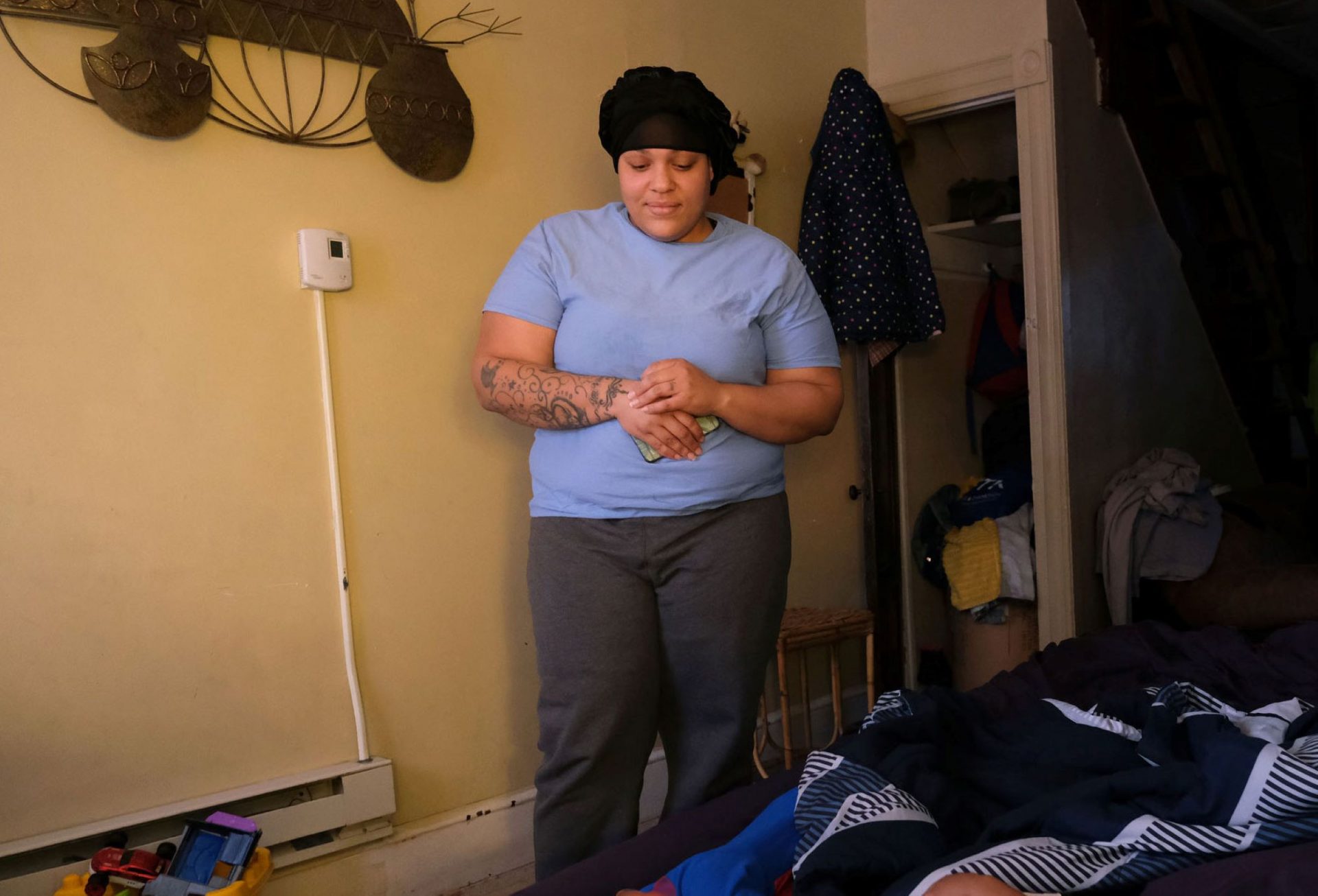 Javonna Lee looks down at her two toddlers on the air mattress where they've been sleeping in her sister's apartment.