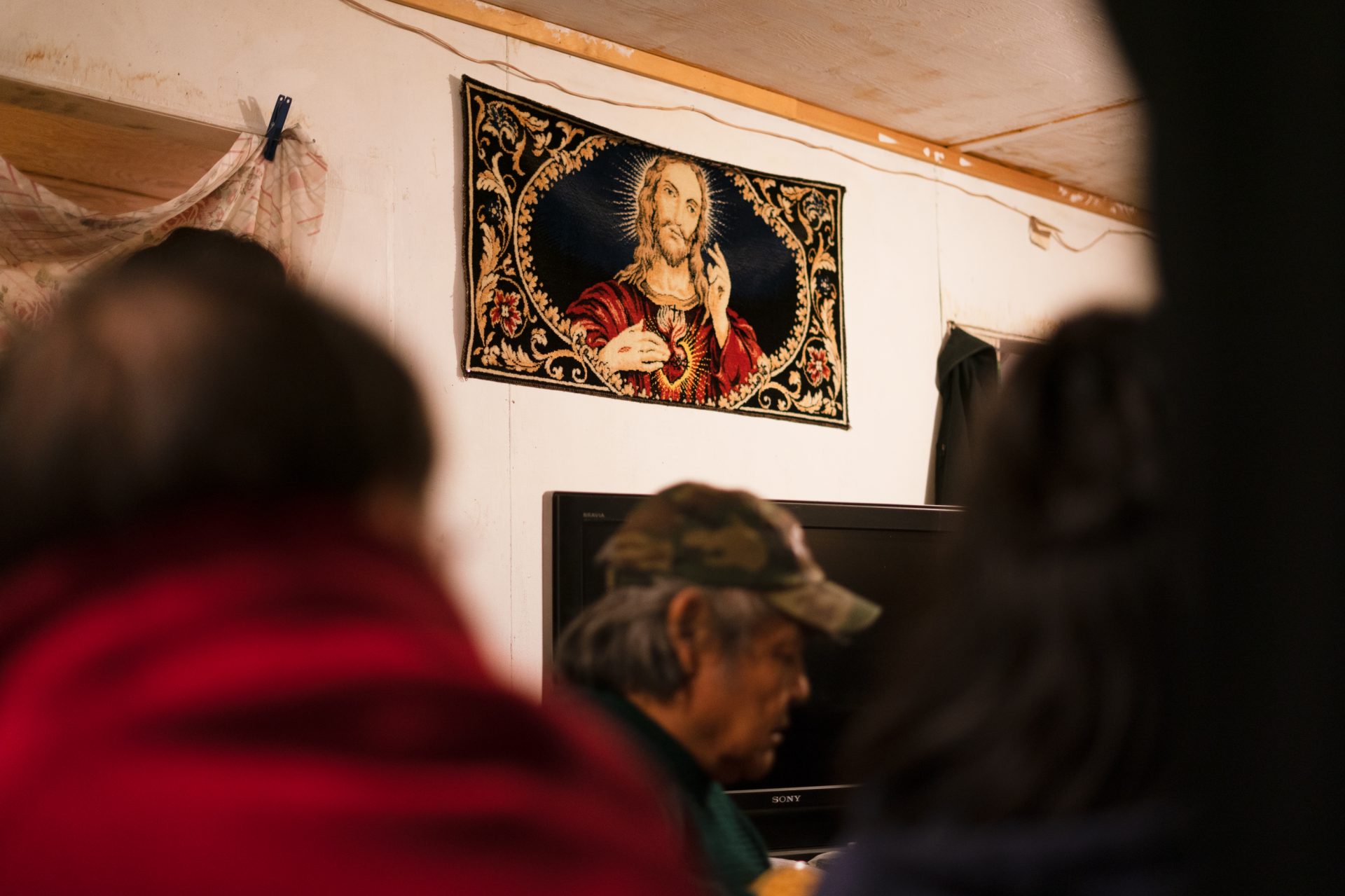 A tapestry depicting Jesus Christ hangs on the wall of a home where friends and family gather to mourn the death of a loved one in Toksook Bay in January.