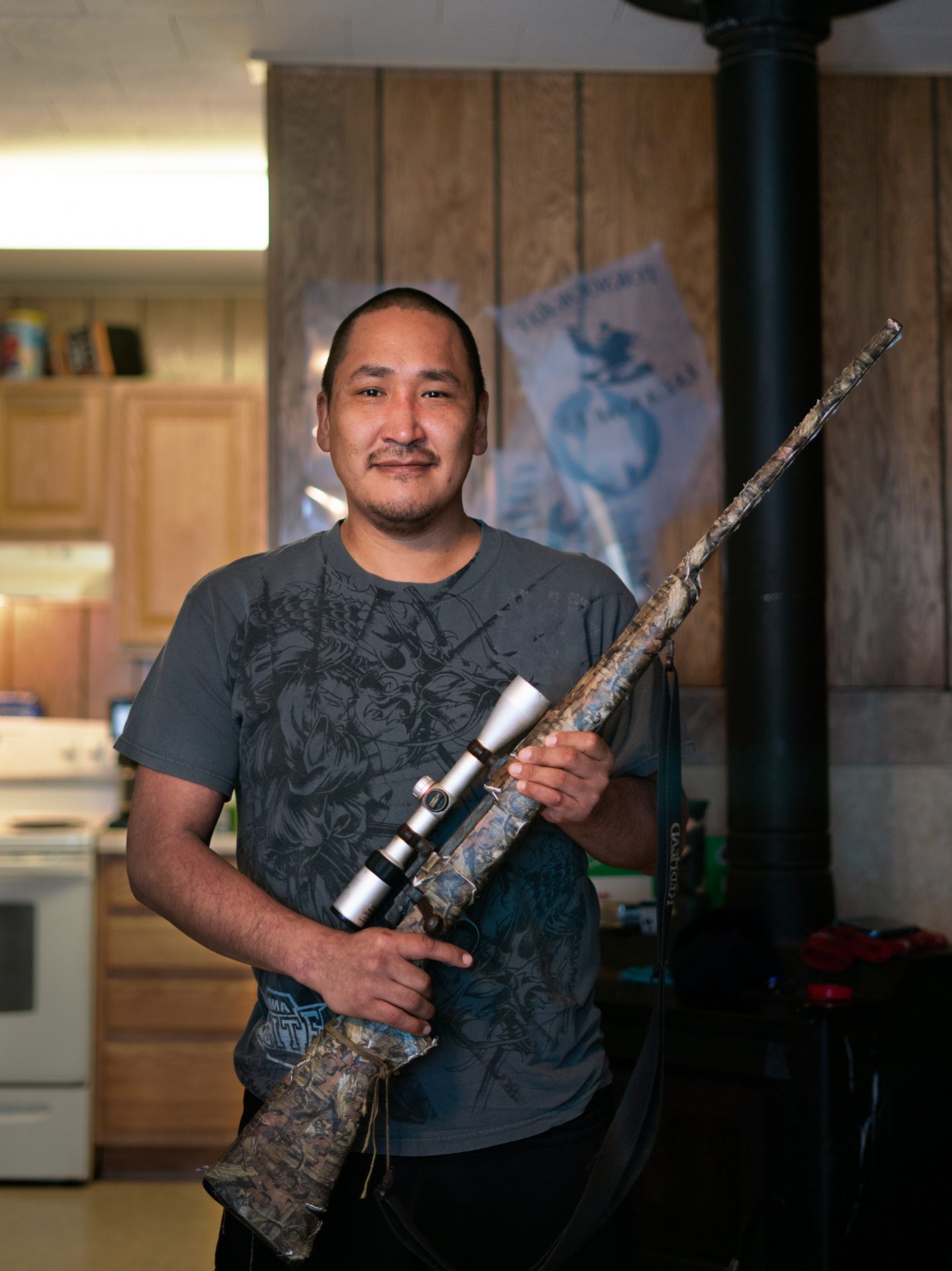 Noah Lincoln holds a gun his family uses for hunting. People in Toksook Bay rely on hunting and other subsistence activities.