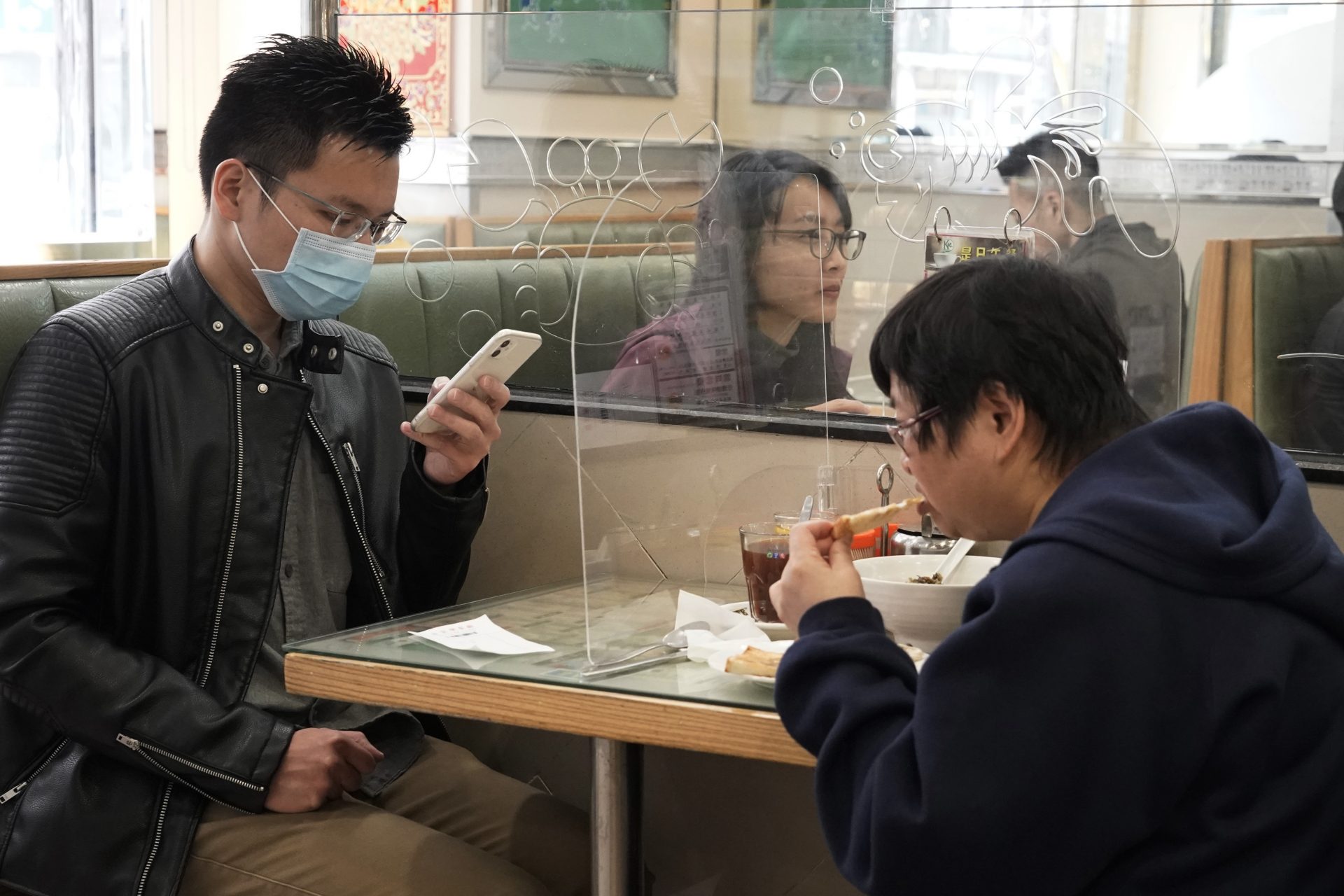 Customers have lunch with a transparent plastic panel setup on the table to isolate each other to prevent spreading of the coronavirus in Hong Kong, Wednesday, Feb. 12, 2020. China's ruling Communist Party needs to make a politically fraught decision: Admit a viral outbreak isn't under control and cancel this year's highest-profile official event. Or bring 3,000 legislators to Beijing next month and risk fueling public anger at the government's handling of the disease.