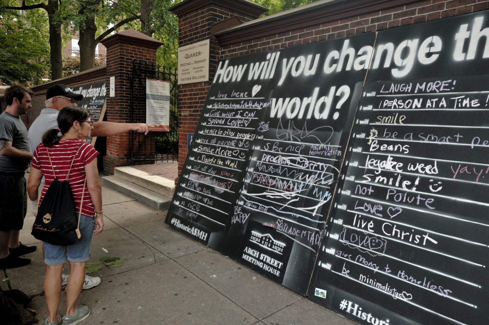 Philadelphia, PA, USA - June 17, 2019; Tourist walk past a large chalk board, that reads How Will You Change The World, outside the historic Arch Street Friends Meeting House in Old City, Philadelphia, PA on June 17, 2019. During the high season large groups of tourists are drawn to the pre-colonial charm of Old City and the historic significance of Independence National Historical Park.