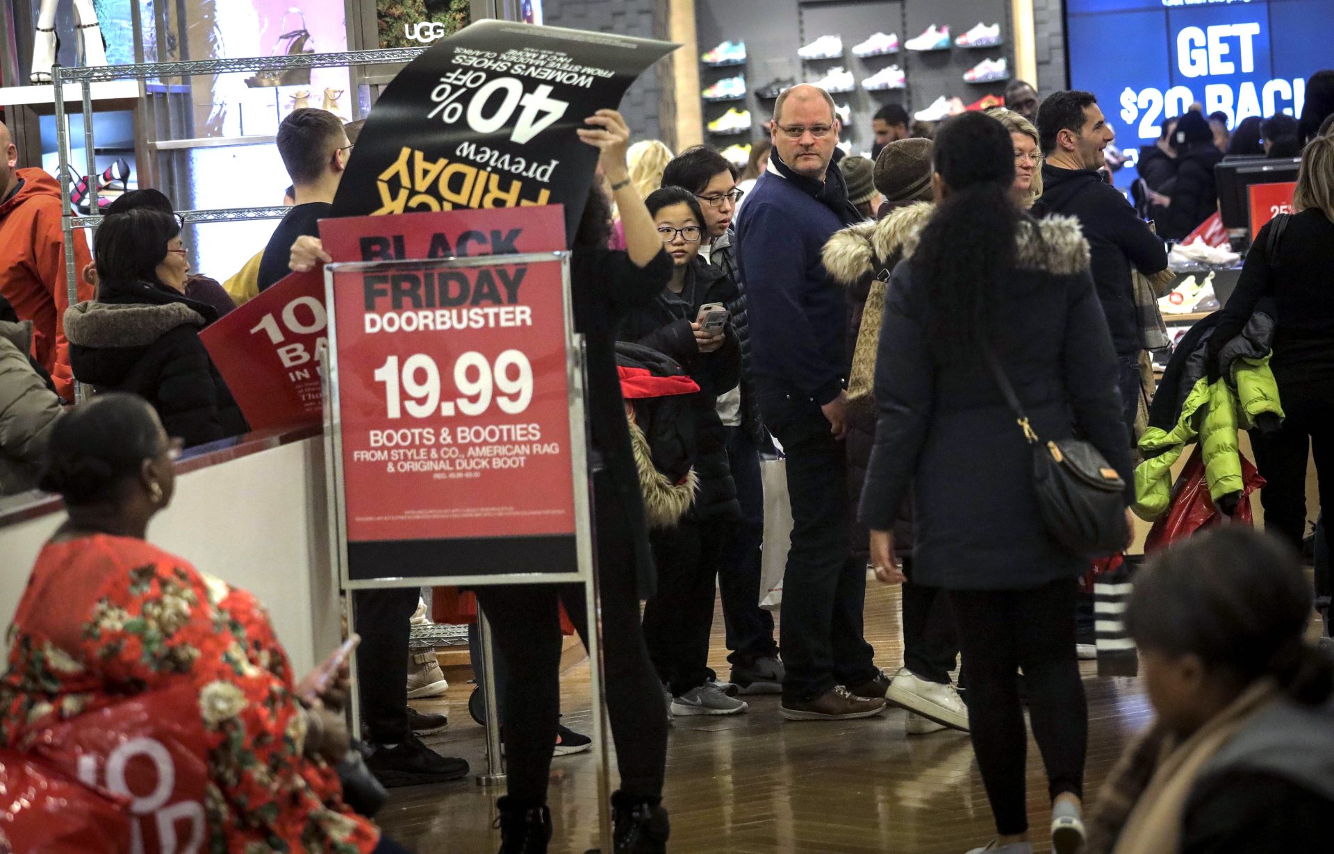 An employee posts discount signs for shoppers at Macy's department store during Black Friday shopping, Friday Nov. 29, 2019, in New York. Black Friday shoppers fought for parking spots and traveled cross-state to their favorite malls, kicking off a shortened shopping season that intensified the mad scramble between Thanksgiving and Christmas.