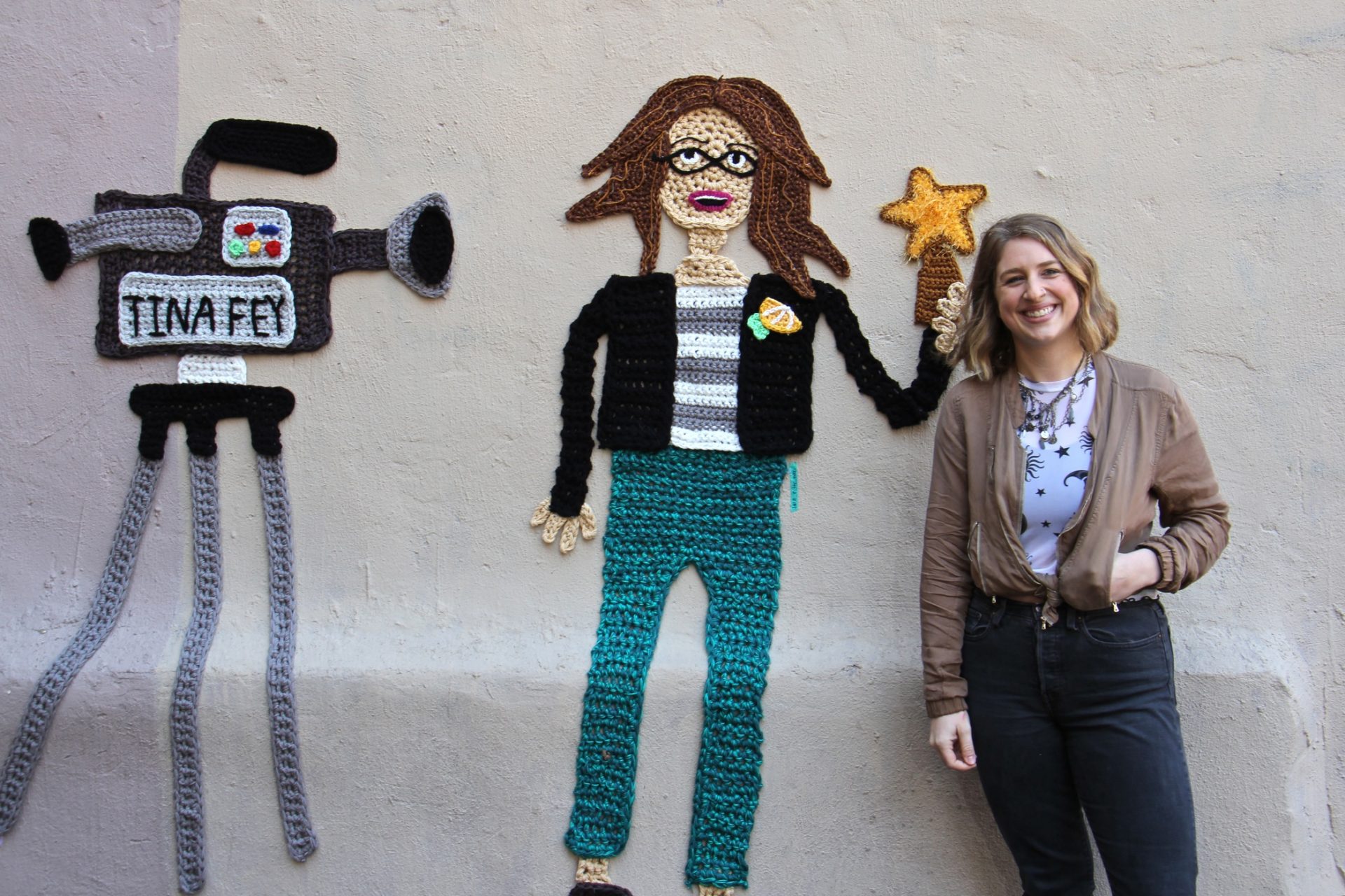 Nicole Nikolich stands beside her yarn bomb portrait of Tina Fey.