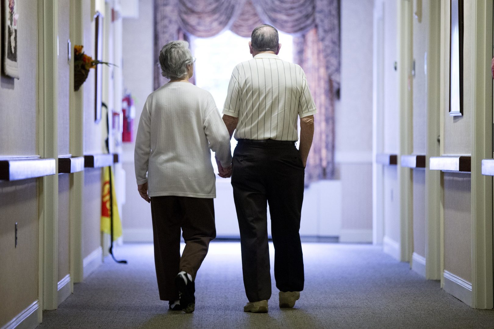 FILE PHOTO: In this Nov. 6, 2015 file photo, an elderly couple walks down a hall of a nursing home in Easton, Pa.
