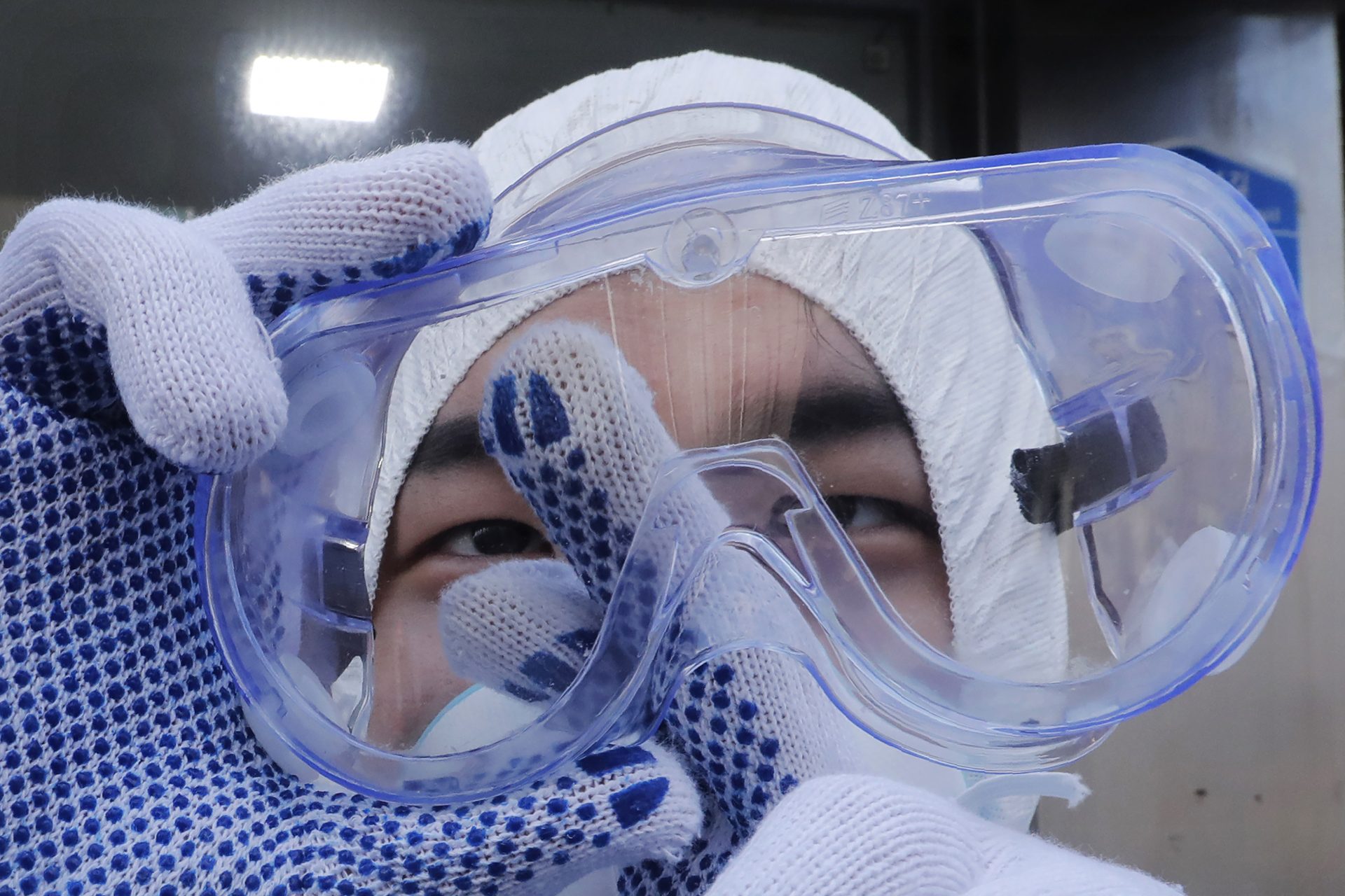 A worker cleans his goggles to spray disinfectant as a precaution against the coronavirus at a shopping street in Seoul, South Korea, Thursday, Feb. 27, 2020.