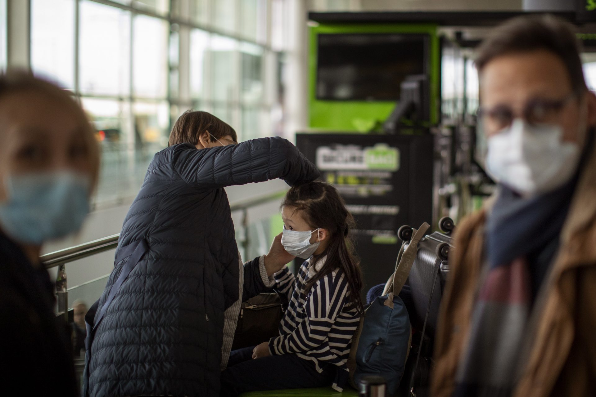 A woman fixes a mask to a child at Barcelona airport, Spain, Thursday, March 12, 2020. President Donald Trump, who had downplayed the coronavirus for weeks, suddenly struck a different tone, announcing strict rules on restricting travel from much of Europe to begin this weekend. For most people, the new coronavirus causes only mild or moderate symptoms, such as fever and cough. For some, especially older adults and people with existing health problems, it can cause more severe illness, including pneumonia.