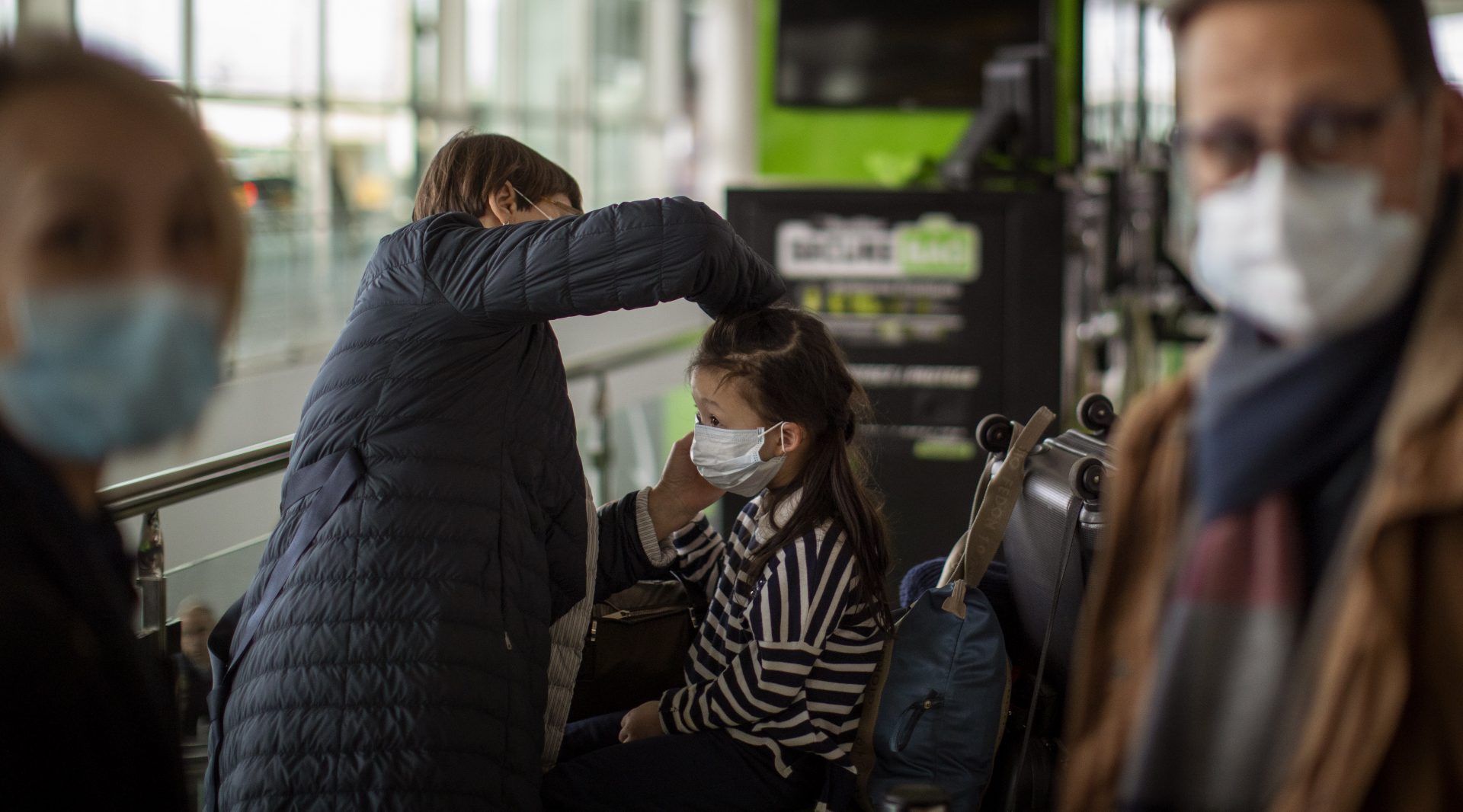 A woman fixes a mask to a child at Barcelona airport, Spain, Thursday, March 12, 2020. President Donald Trump, who had downplayed the coronavirus for weeks, suddenly struck a different tone, announcing strict rules on restricting travel from much of Europe to begin this weekend. For most people, the new coronavirus causes only mild or moderate symptoms, such as fever and cough. For some, especially older adults and people with existing health problems, it can cause more severe illness, including pneumonia.