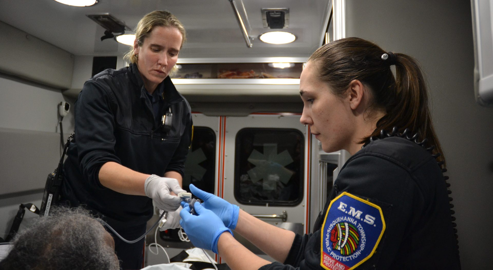 Paramedic Julia Hanson, left, and emergency medical technician Justine Berry, right, check their patient’s vital signs. Emergency services workers are at increased risk for contracting and spreading infectious diseases.