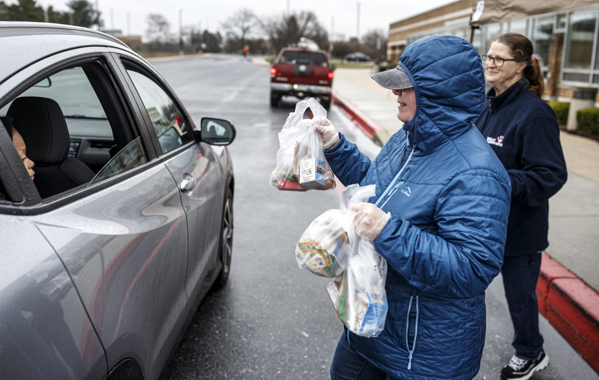 Kim Farris, left, and Cynthia Euler deliver meals to a family at Central Dauphin East High School. During the coronavirus COVID-19 shutdown, drive-through distribution of breakfast and lunch will be available each weekday from 8:30 a.m. through 11:00 a.m. at Central Dauphin East High School and Swatara Middle School. This first-come, first-served program is for all resident children in the district ages 18 and under, March 17, 2020.