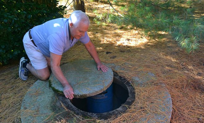 Jerry Solomon, of West Lampeter Township, rolls the stone slab that covers his private well water pump at the back of his home on Dec. 9, 2019. Solomon's well was tested three times, the first time the results showed nitrate levels more than two limes the Environmental Protection Agency maximum limits for public drinking water systems.