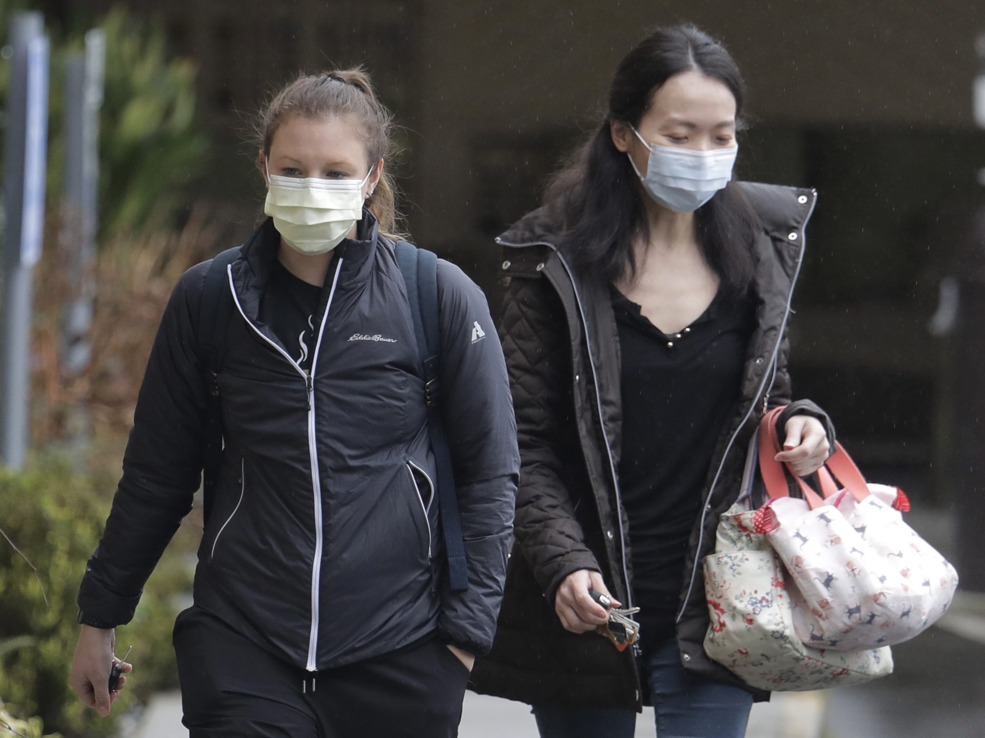 Two women wearing masks walk away from the Life Care Center in Kirkland, Wash., near Seattle, where health officials are monitoring patients. An outbreak of the coronavirus is cited as the cause for two  deaths of patients who received care at the center.